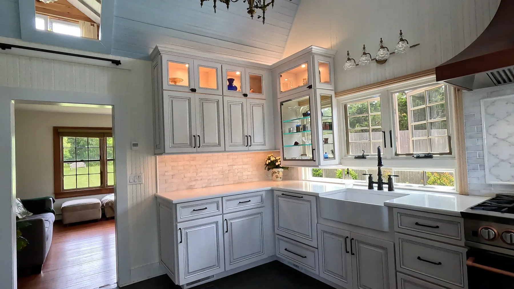 Una cocina luminosa con gabinetes blancos, ventanas amplias y una superficie central de trabajo.