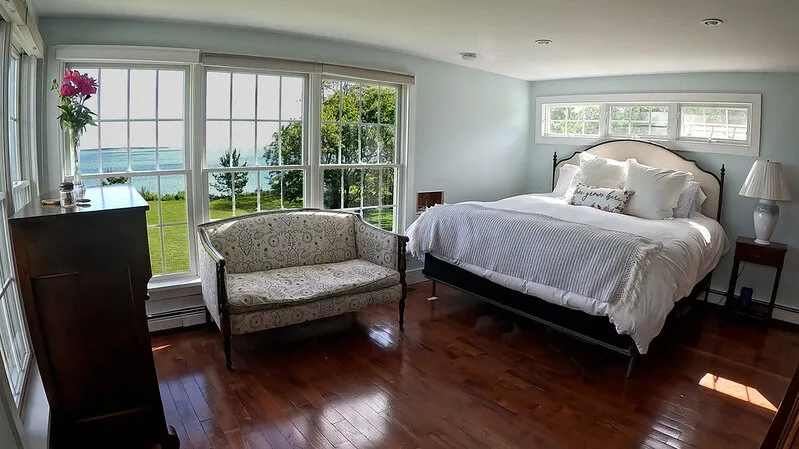 Un dormitorio con una cama y una pequeña zona de estar junto a grandes ventanas.