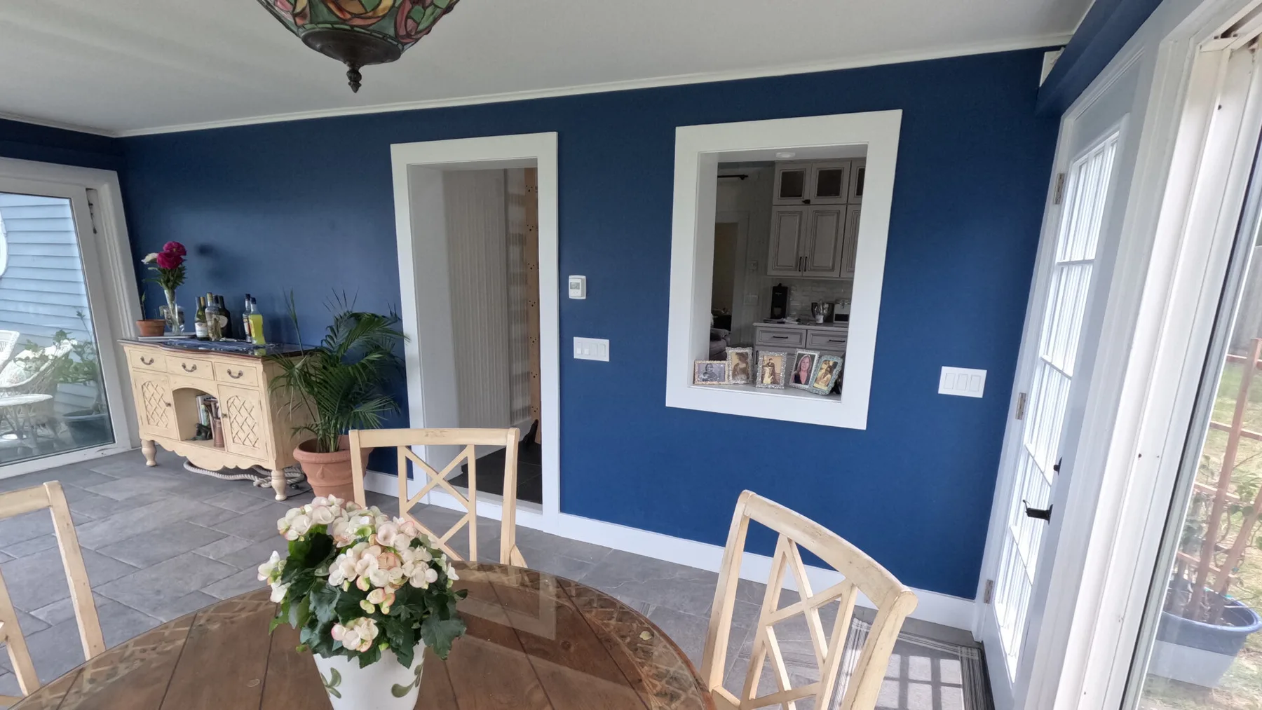 Un comedor con una mesa redonda de madera y un centro floral junto a paredes azules.