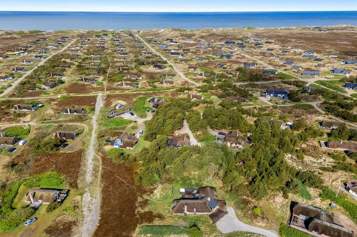 Vista aérea de casas dispersas y caminos cerca de la costa.