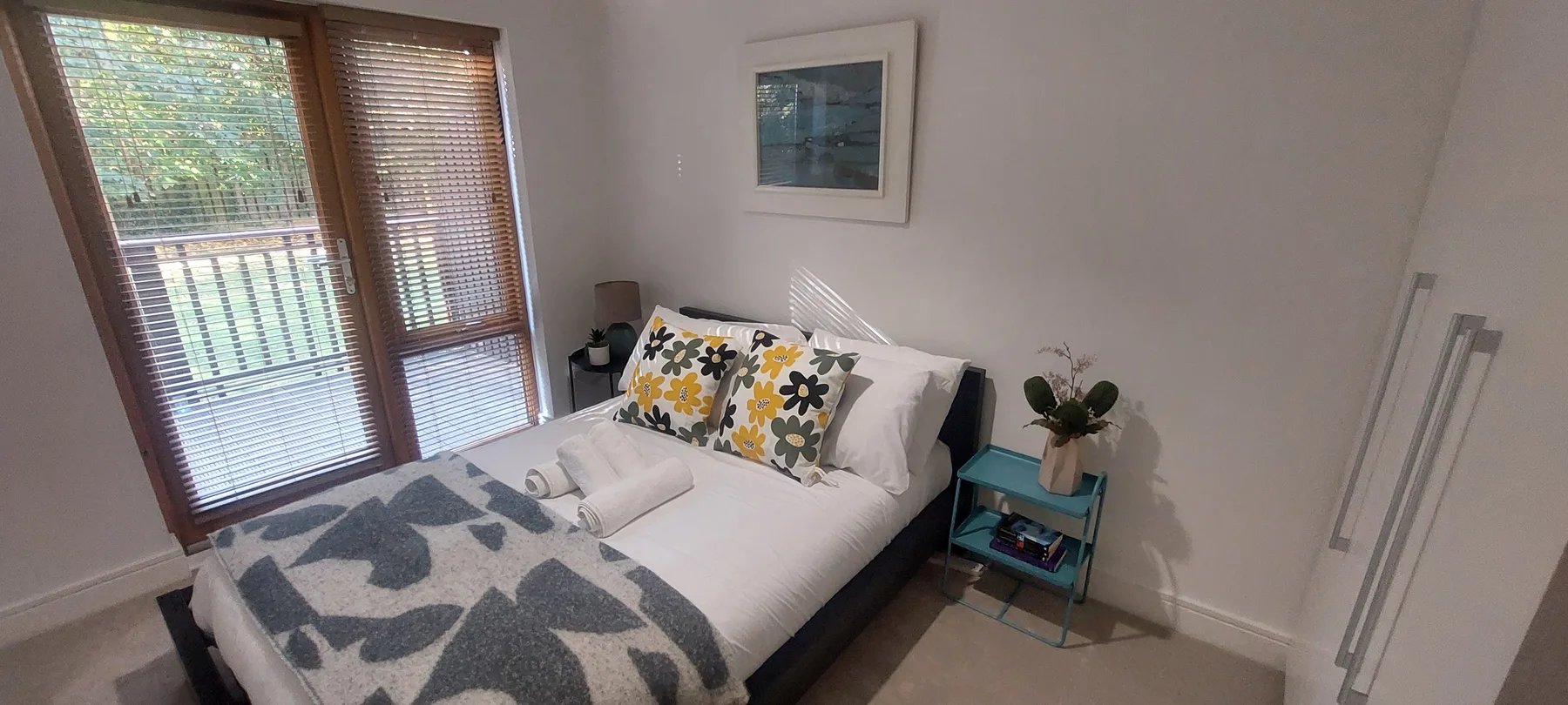Un dormitorio con una cama, ropa de cama estampada y una ventana con persianas.