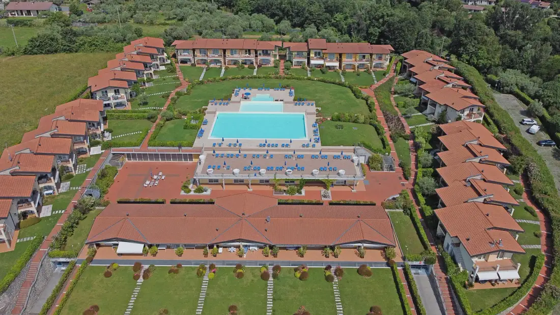 Vista aérea de un complejo turístico dispuesto alrededor de una piscina.