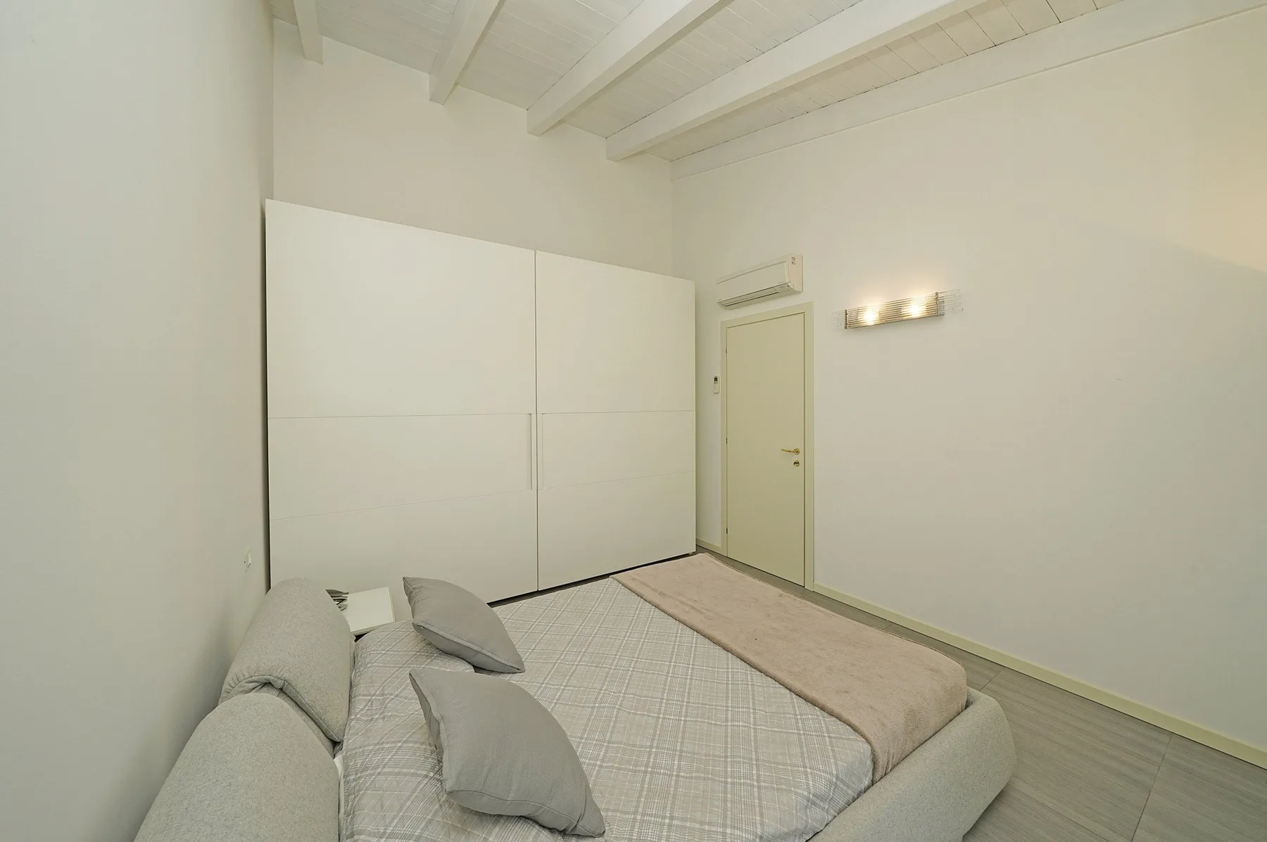 Un dormitorio con una cama, un armario grande y una puerta.