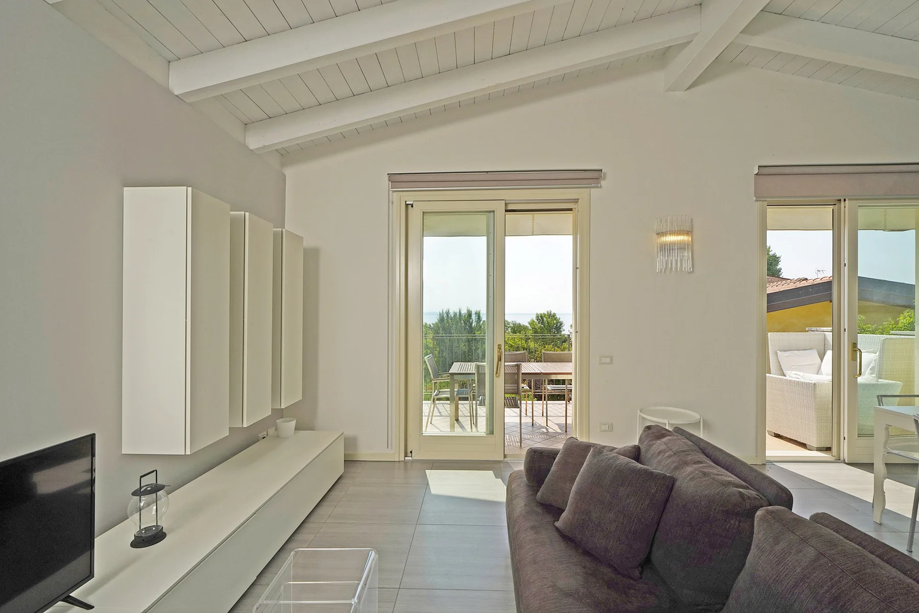 Una sala luminosa da a un patio a través de grandes puertas de vidrio.