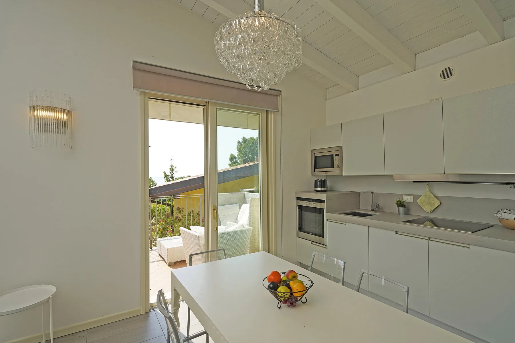 Una cocina luminosa con comedor se abre a una terraza mediante puertas corredizas de vidrio.