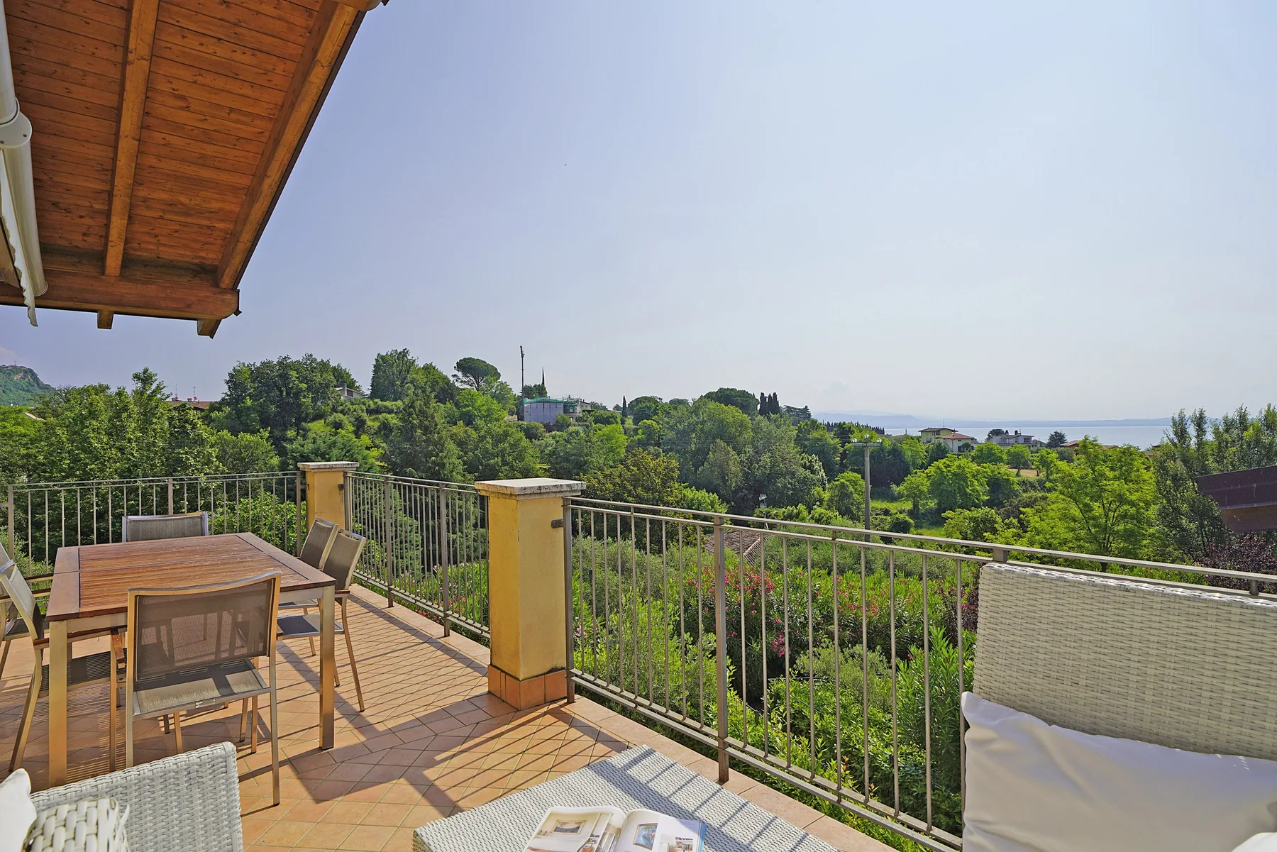 Una terraza amueblada al aire libre ofrece vistas a un paisaje verde bajo un toldo de madera.