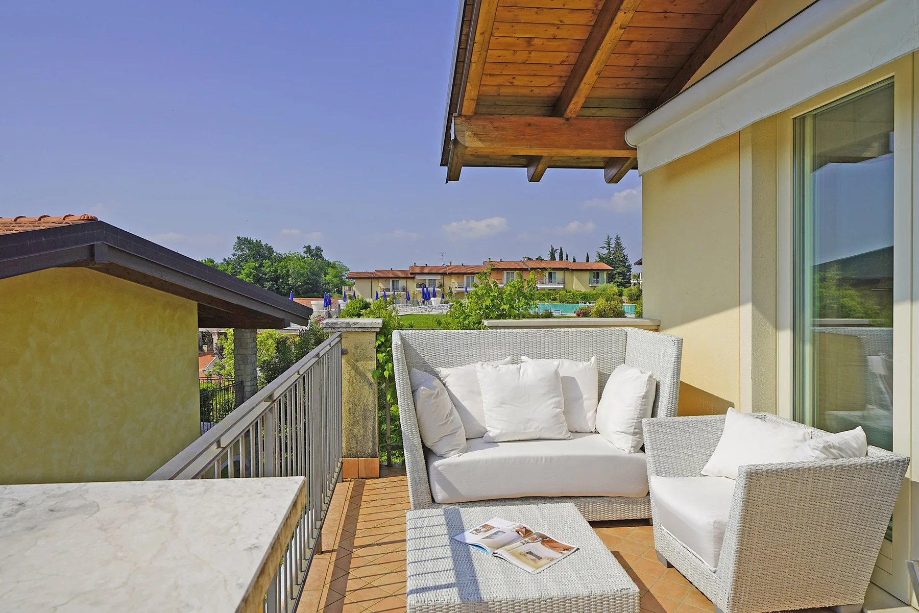 Una terraza amueblada al aire libre con asientos claros y una mesa.