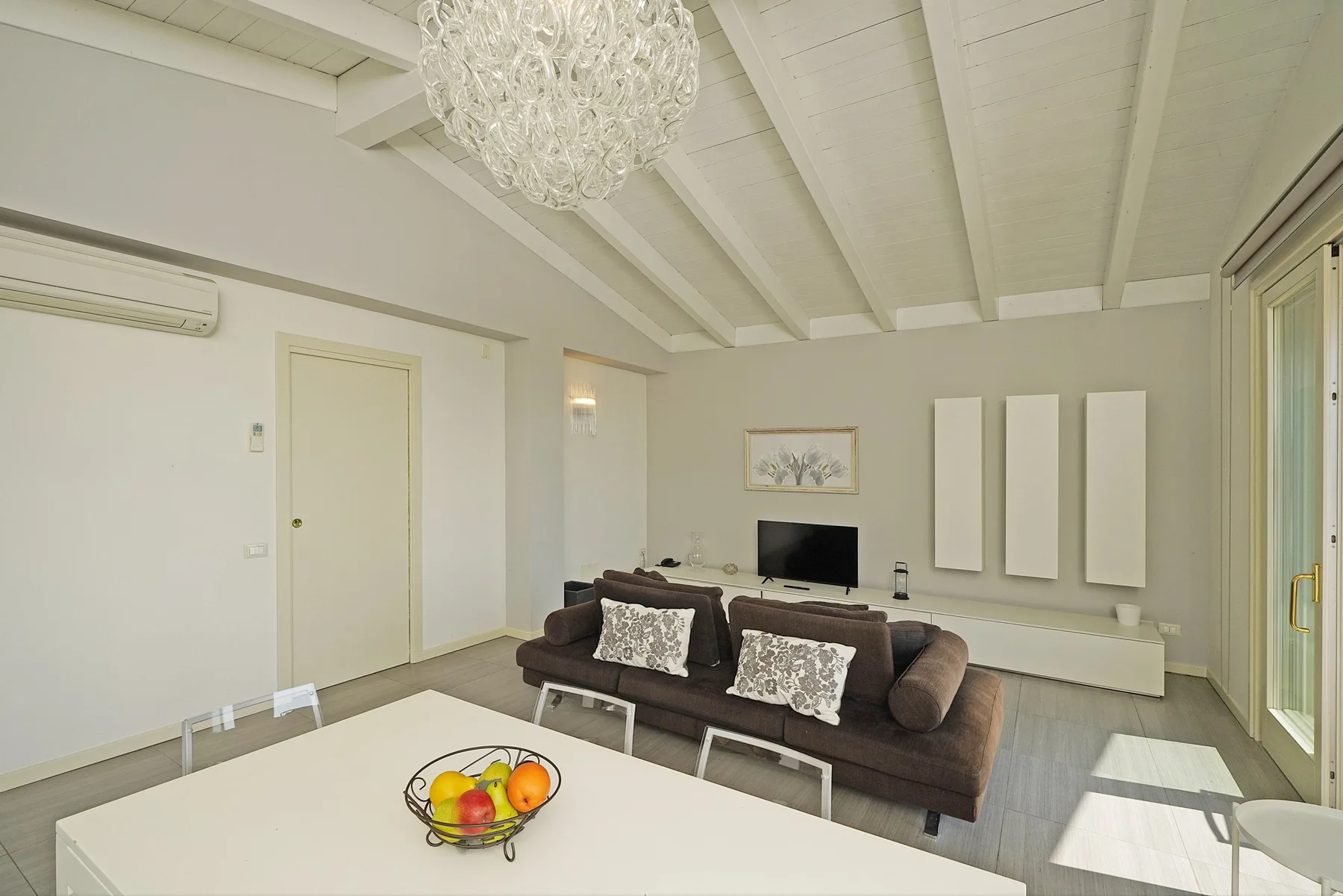 Una sala luminosa con un sofá oscuro y una mesa de comedor en primer plano.