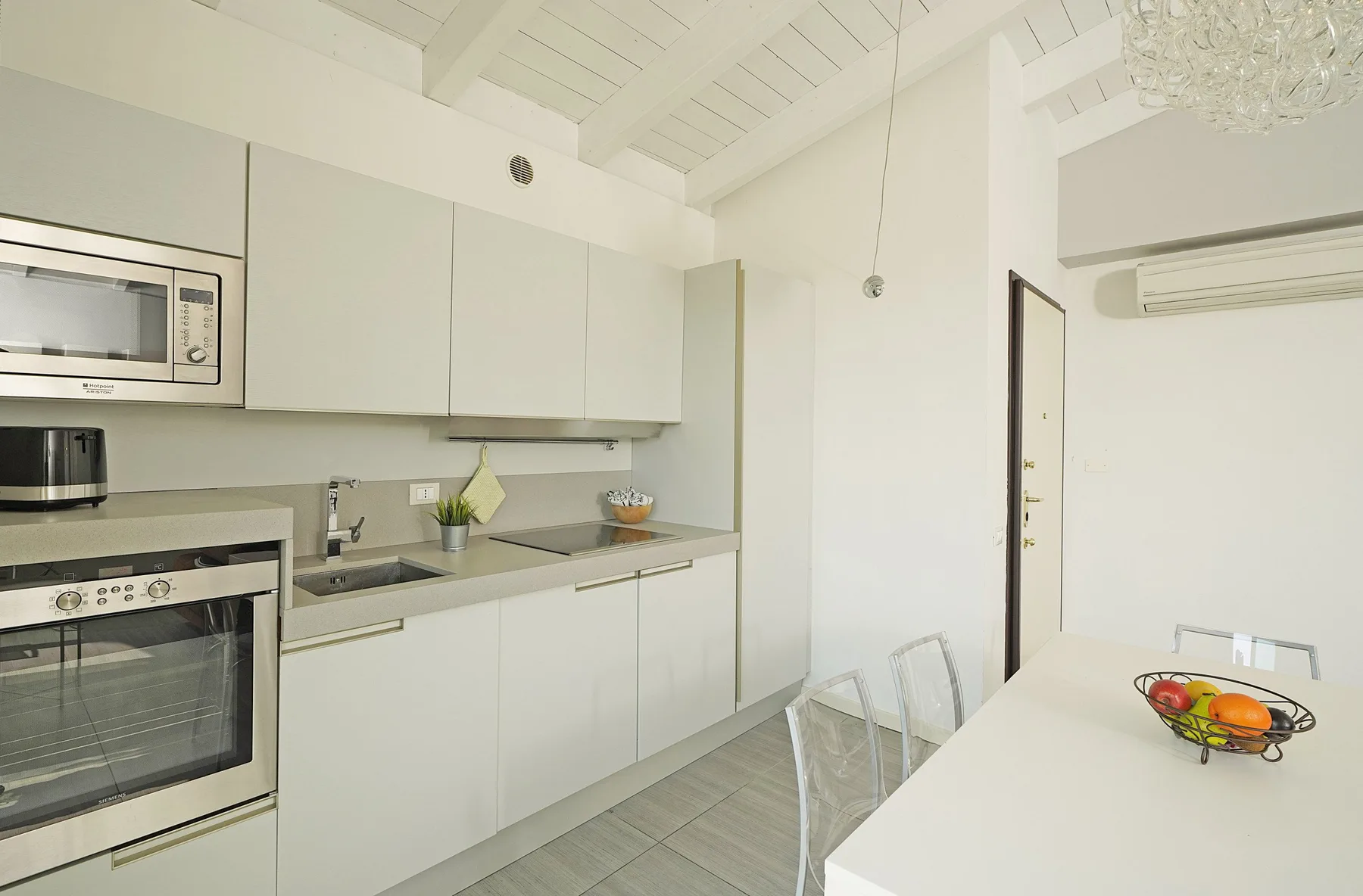 Una cocina luminosa con gabinetes blancos, electrodomésticos integrados y una mesa de comedor.