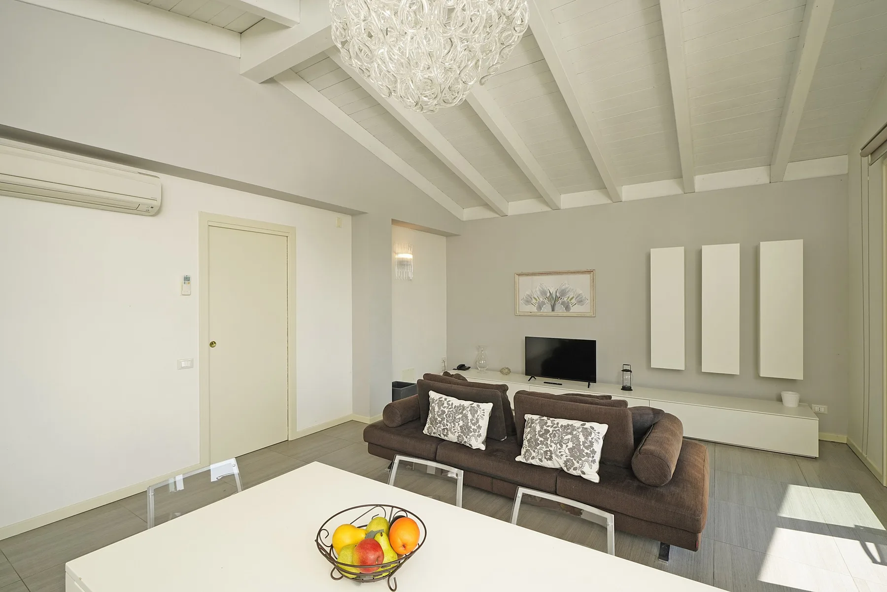 Una sala luminosa con asientos, un televisor y una mesa de comedor.