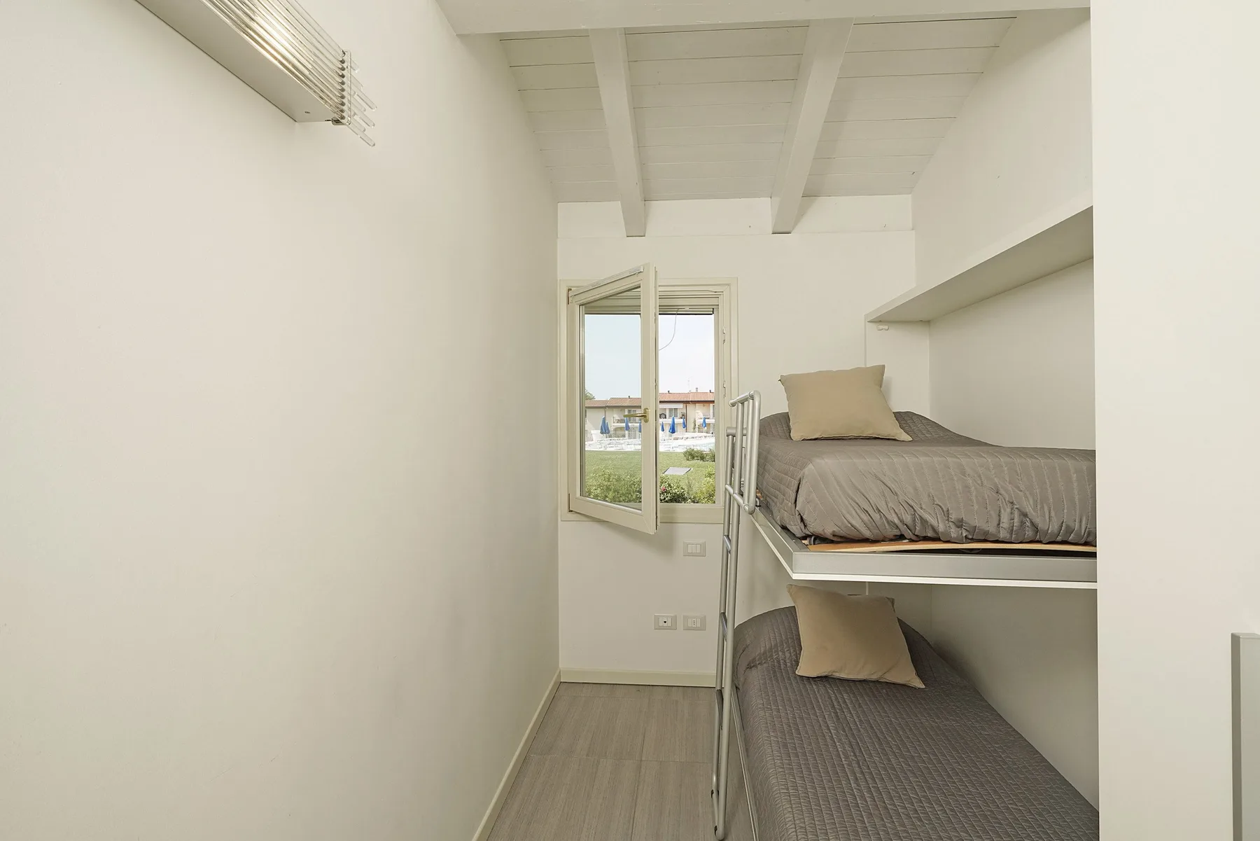 Un dormitorio compacto con dos camas apiladas y una ventana.
