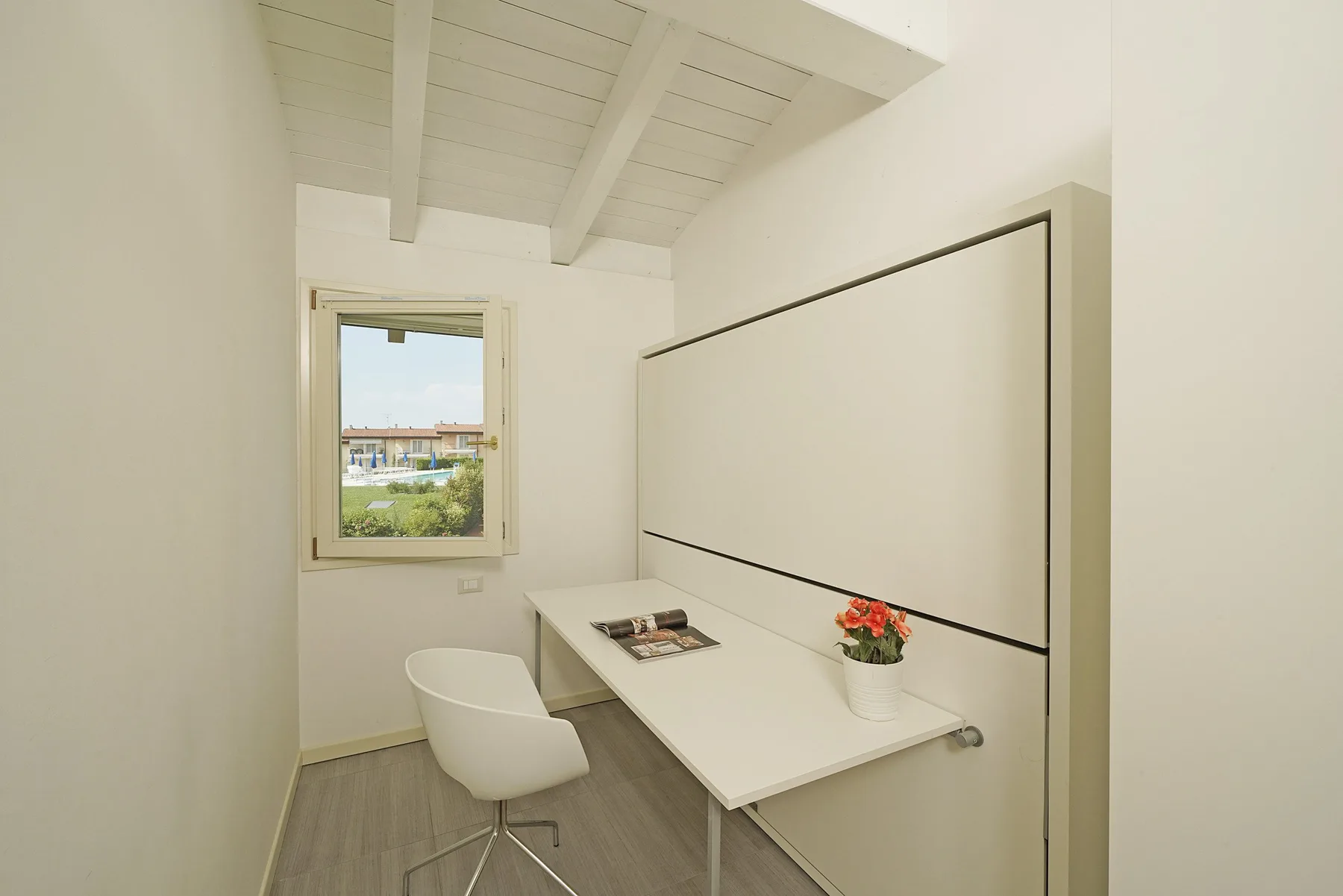 Un espacio de trabajo compacto con un escritorio de pared y una ventana.