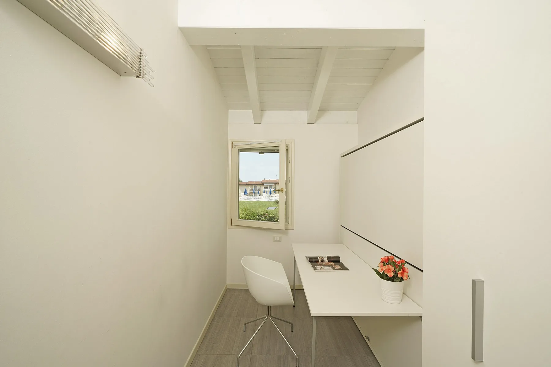 Un pequeño espacio de escritorio con una ventana y un arreglo floral.