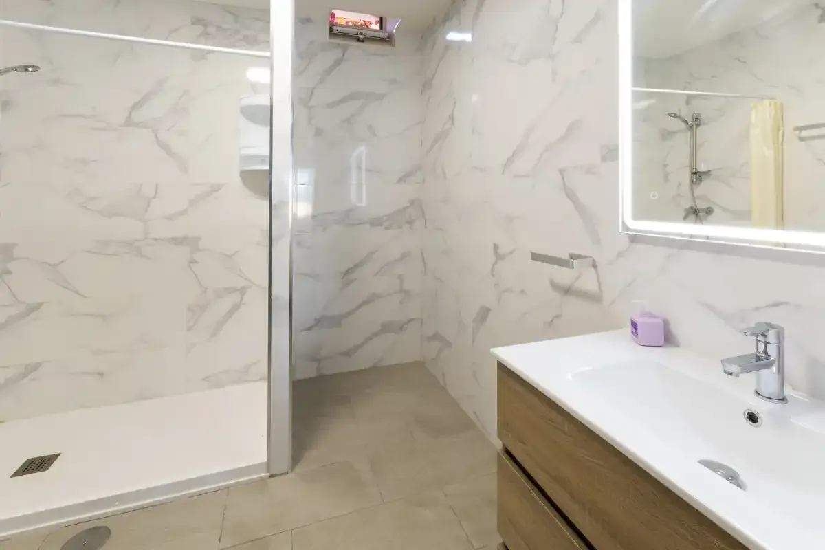 A bathroom with a walk-in shower and a vanity beside a large mirror.