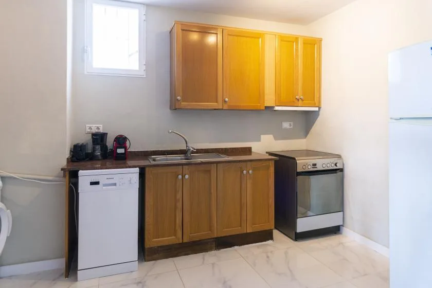 A compact kitchen with wooden cabinets, a sink, and a stove.
