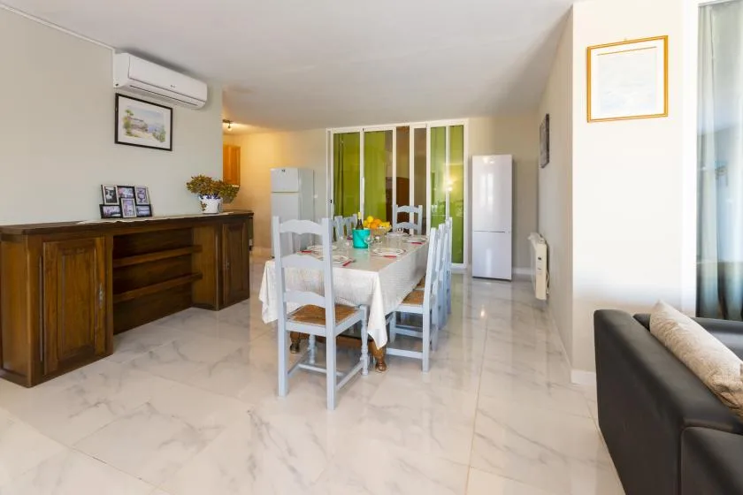 A dining area with a table and chairs stands between a wooden cabinet and glass doors.