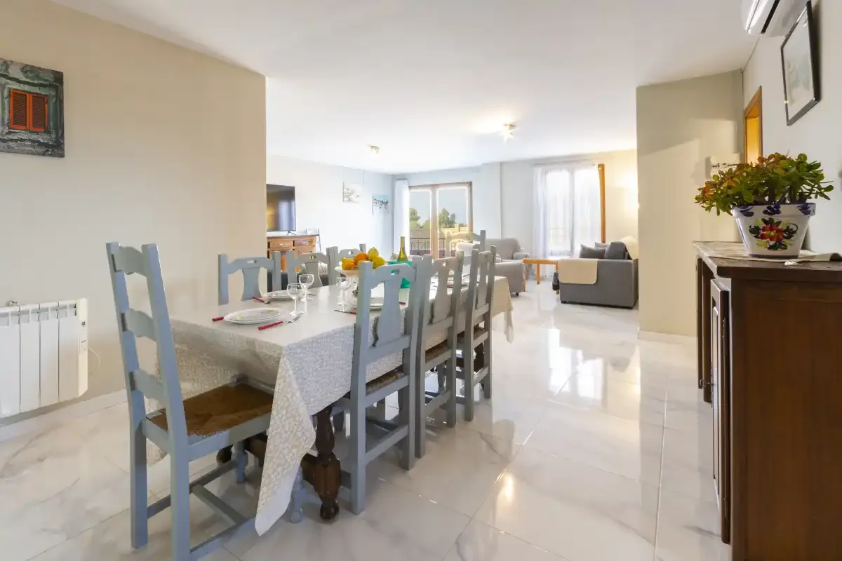 A bright dining and living area with a long table and seating.