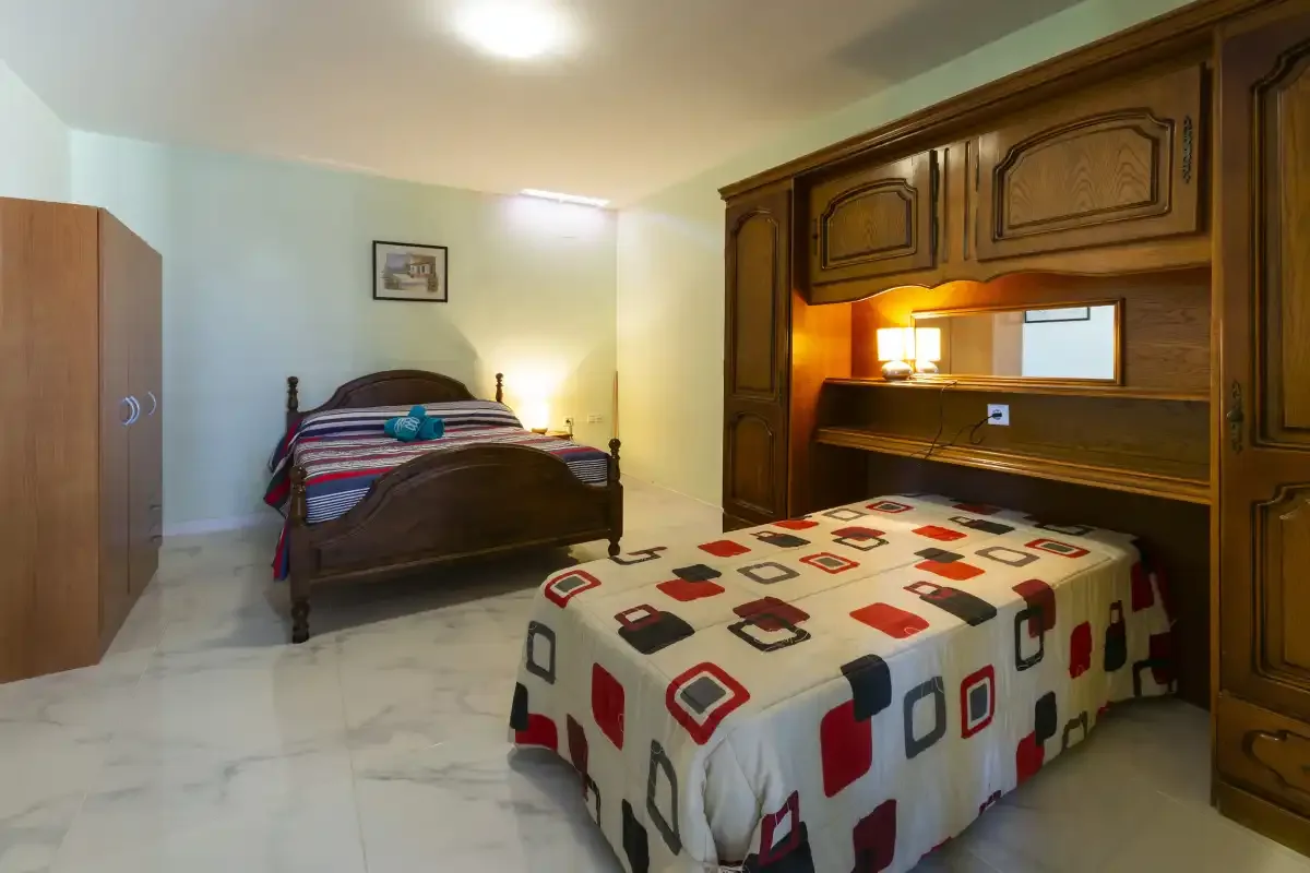 A bedroom with two beds and a large wooden built-in unit.