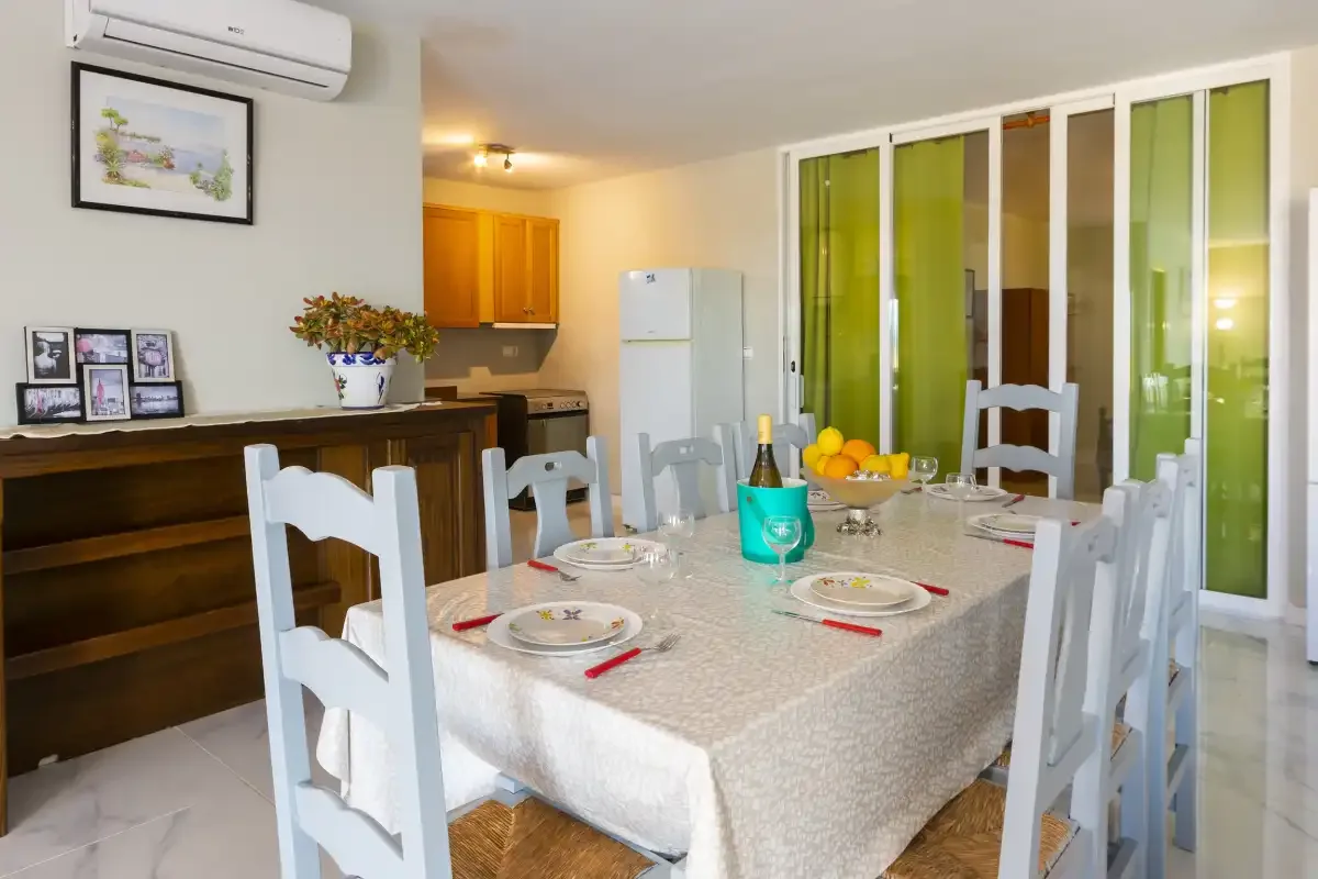 A dining area with a set table and a kitchen in the background.
