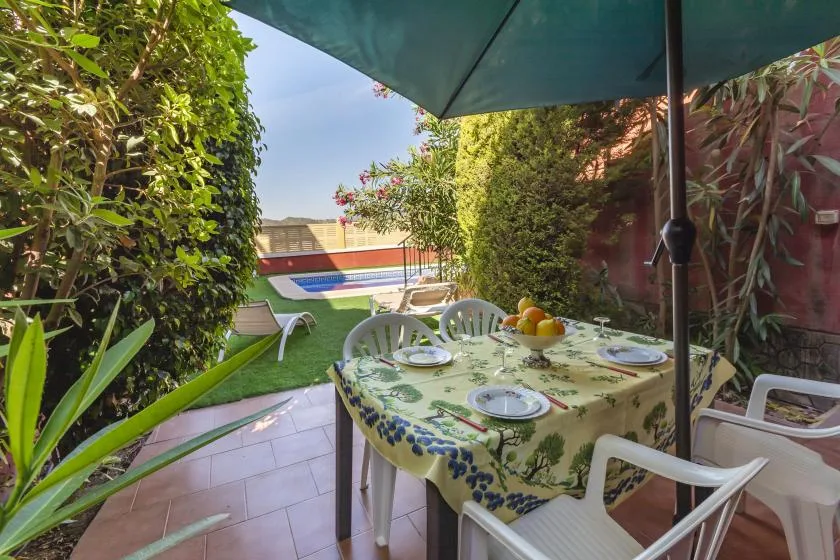 An outdoor patio dining area with a table beneath a large umbrella.