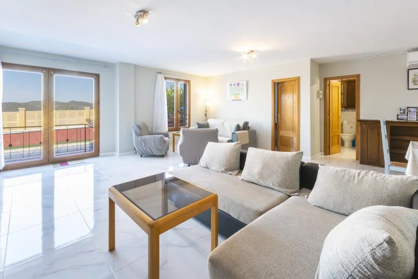 A bright living room with a sectional seating area and glass coffee table.