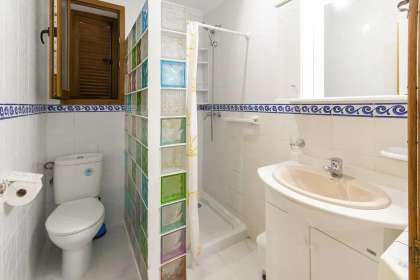A bathroom with a toilet, sink, and shower behind a curtain.