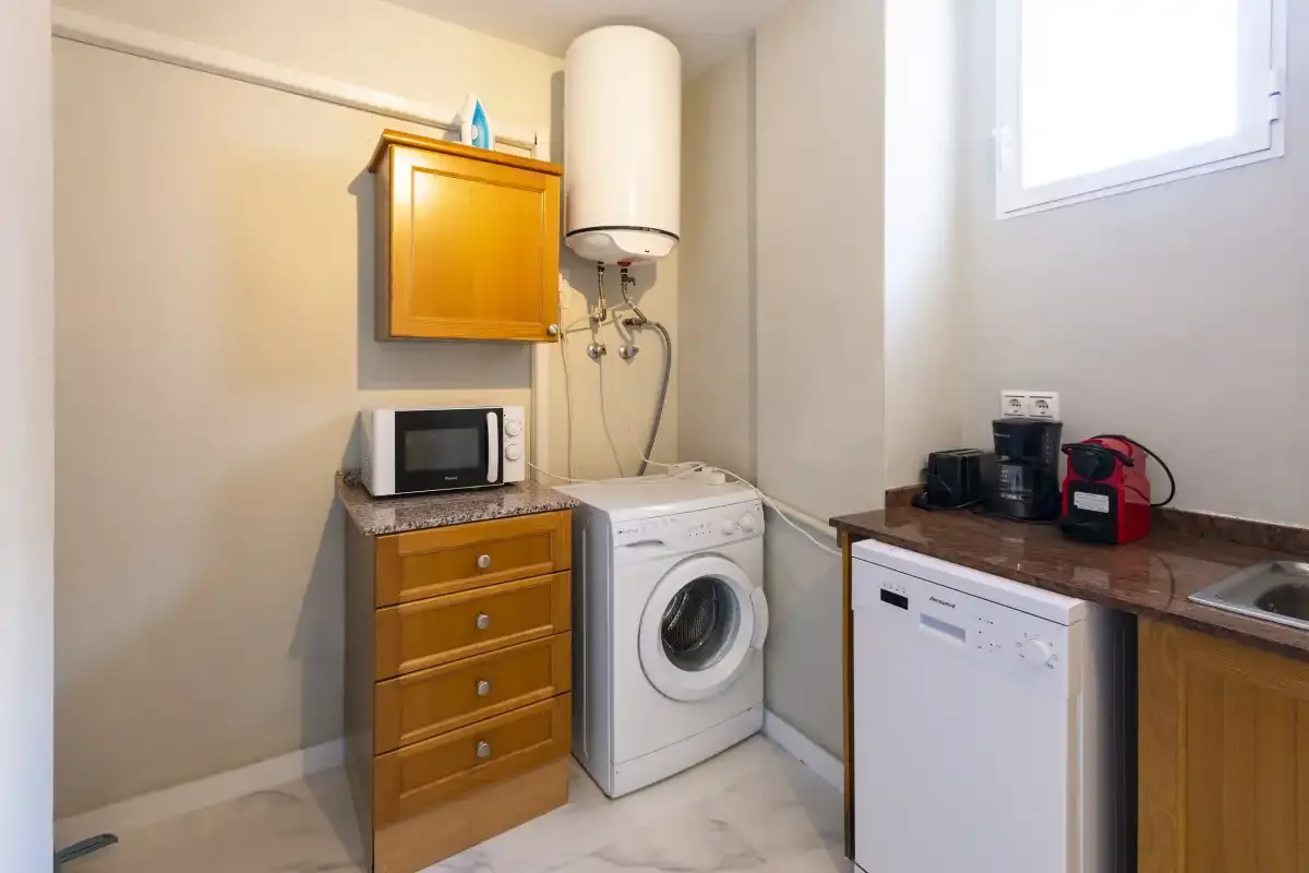 A laundry area with a washing machine, countertop, and small appliances.