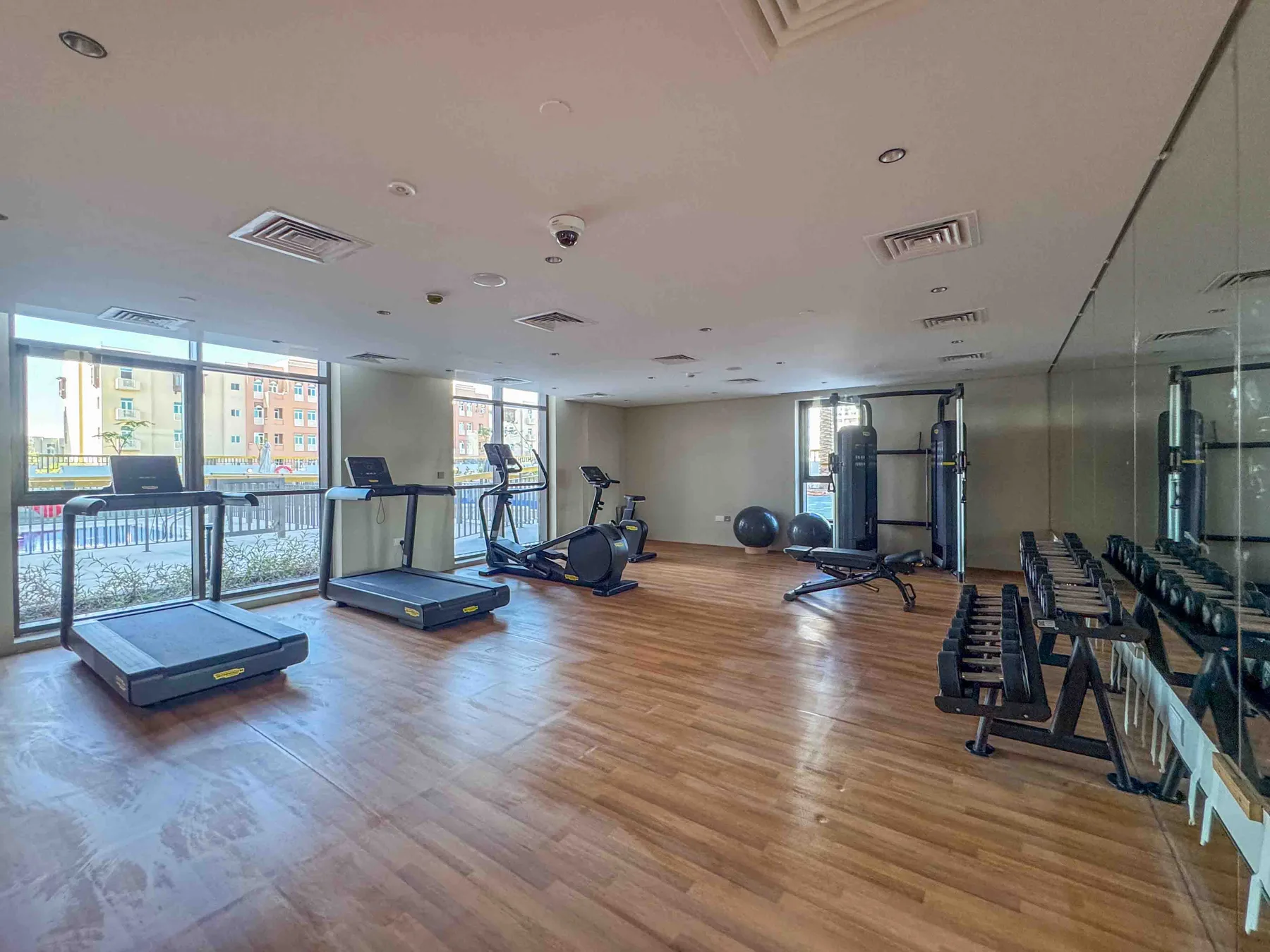 Una sala de ejercicio con máquinas, pesas y una pared con espejo.