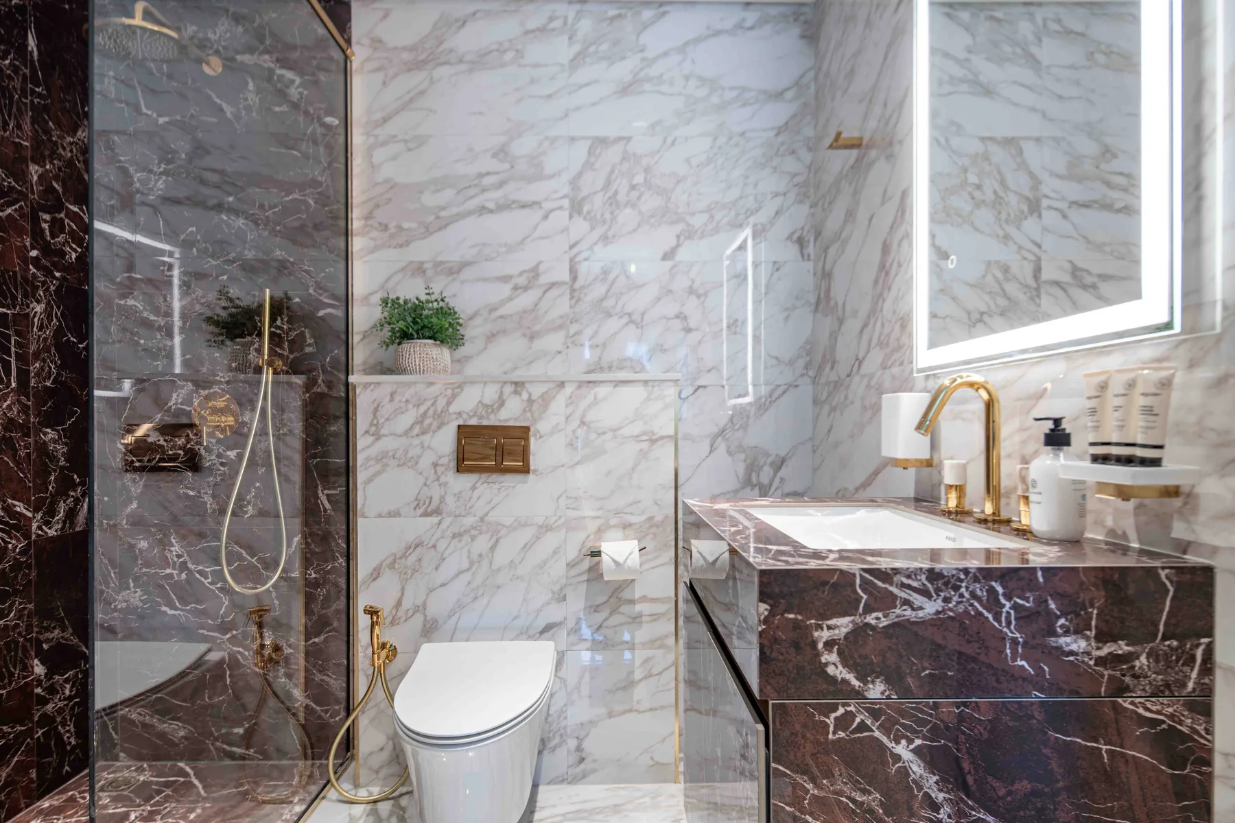 Un baño de mármol con ducha de vidrio, inodoro y lavabo.