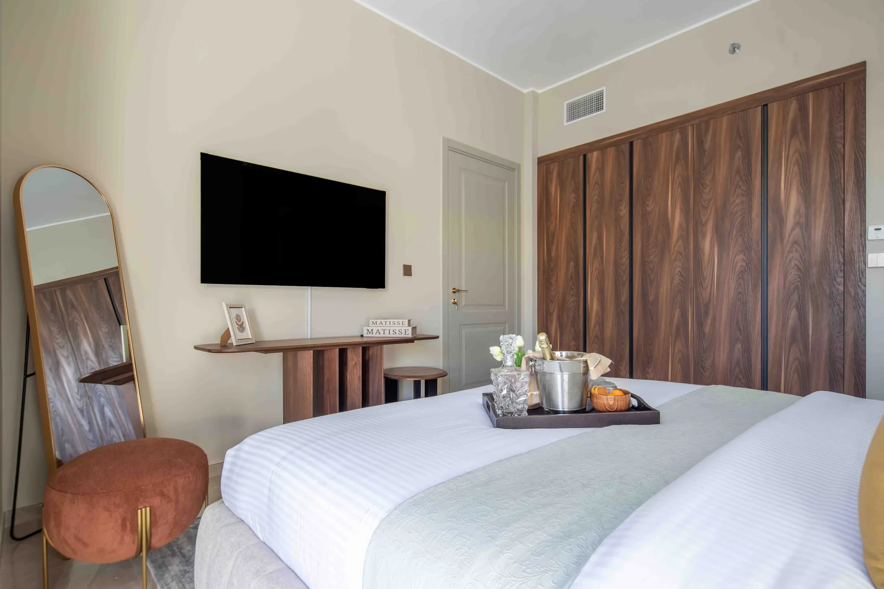Un dormitorio con un televisor en la pared y una bandeja sobre la cama.