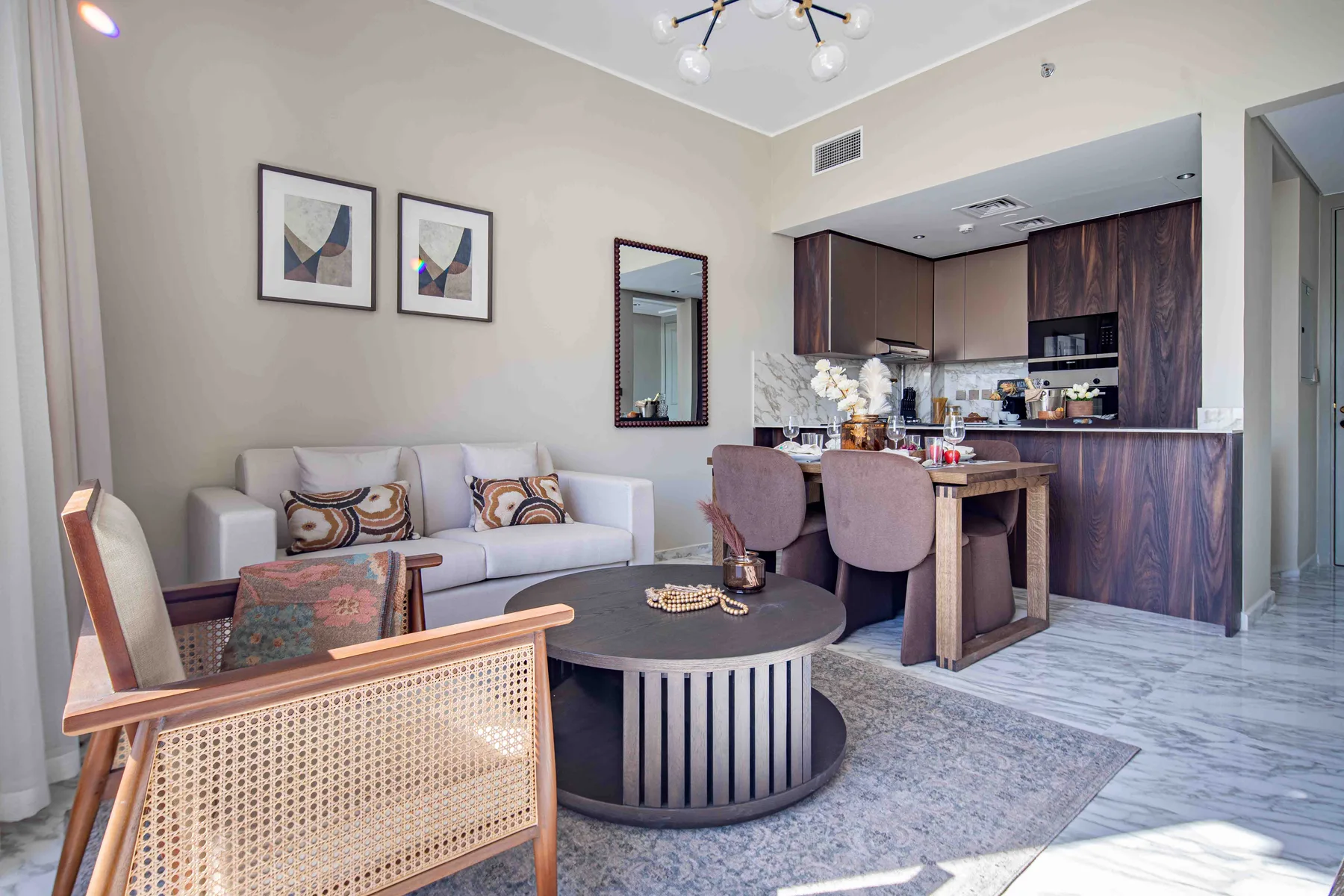 Una sala de estar con asientos y una mesa de centro redonda junto a una cocina abierta.