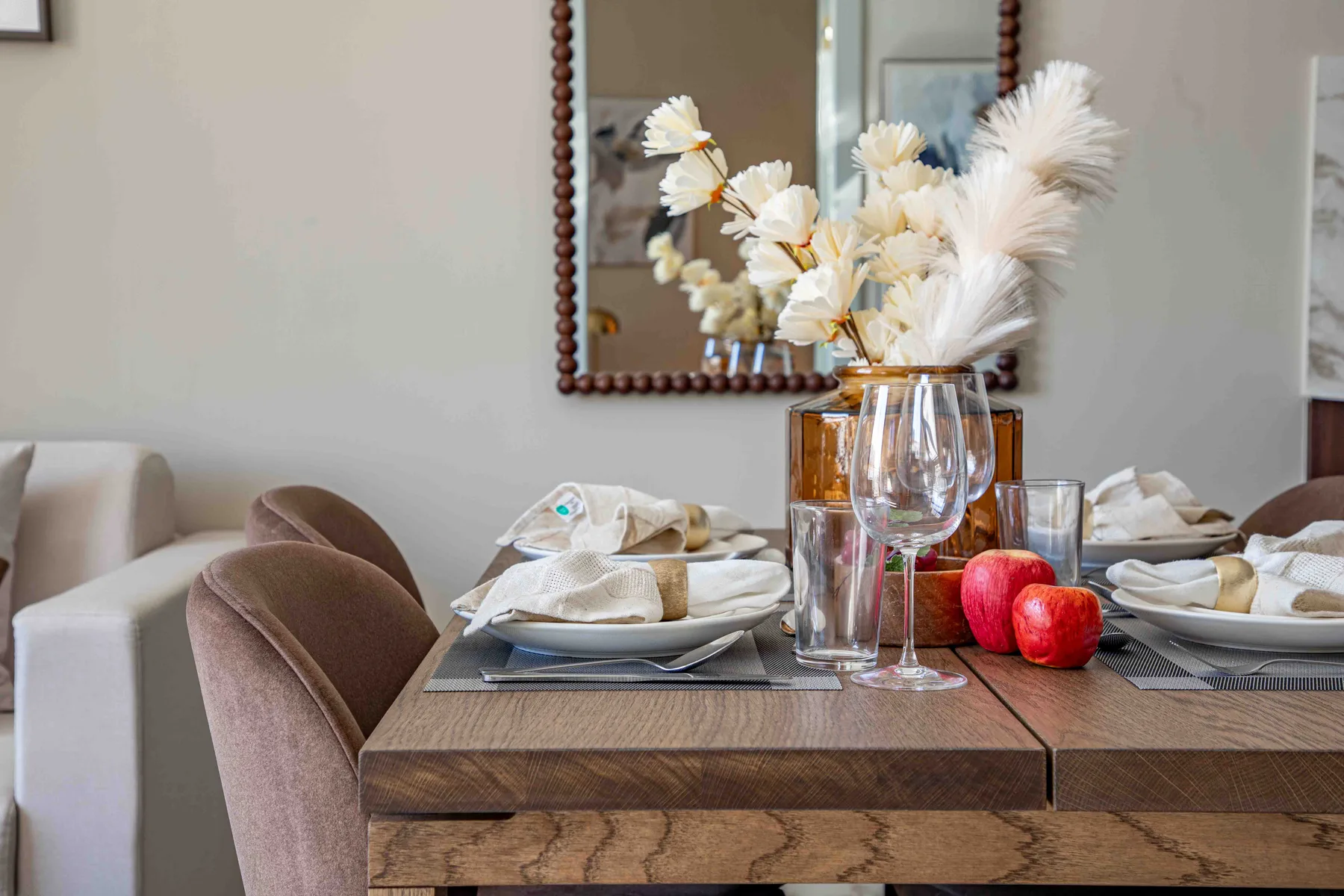 Una mesa de comedor está puesta con platos, copas y un jarrón de flores.