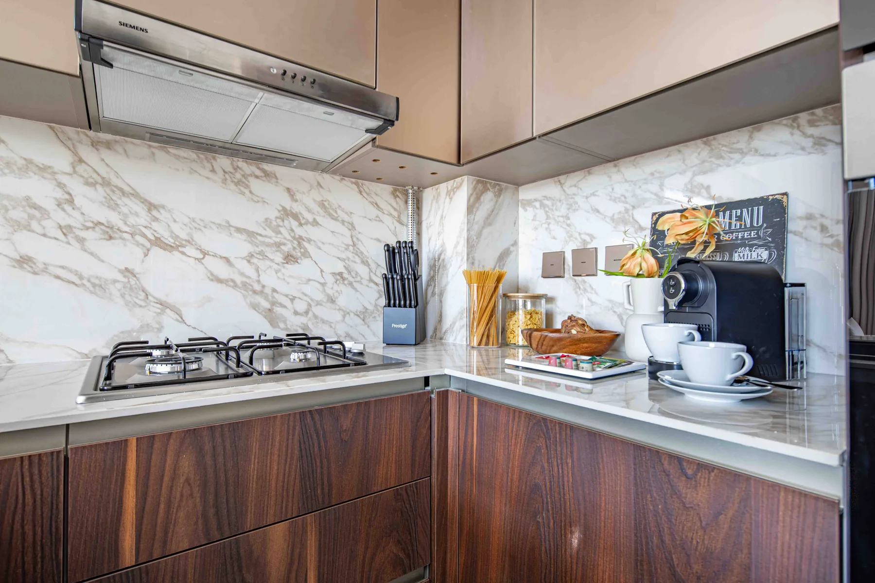 Una cocina con una estufa de gas, electrodomésticos sobre la encimera y gabinetes de madera.