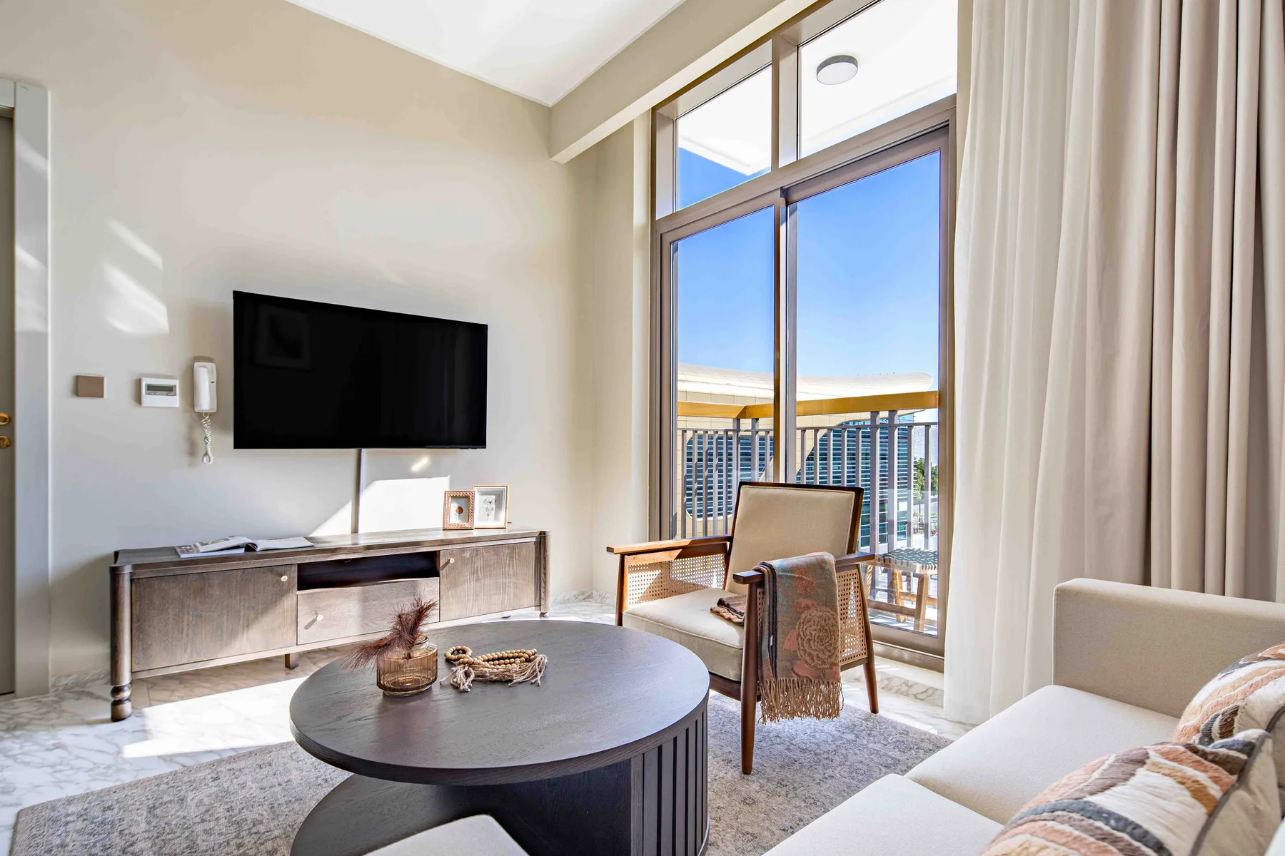 Sala de estar con televisión y ventanales hacia un balcón.