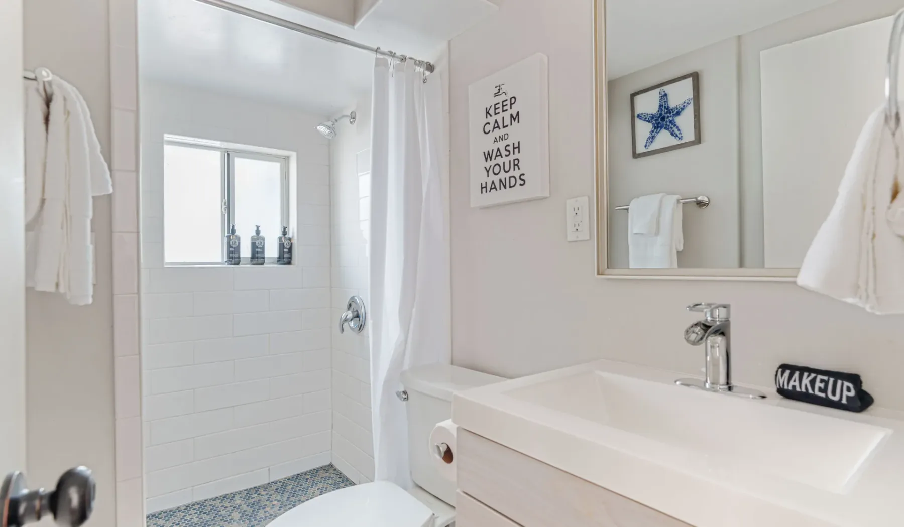 Un baño luminoso con bañera, ducha y un espejo grande en la pared.