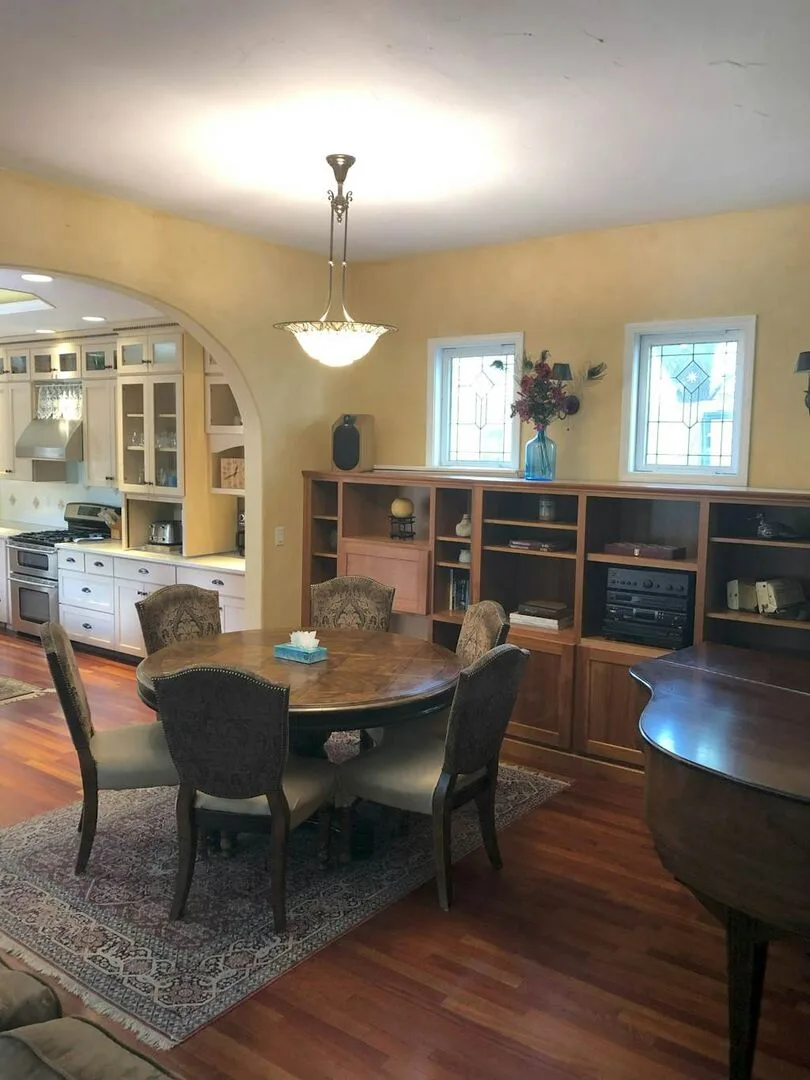 A dining area with a round table and built-in shelving along the wall.