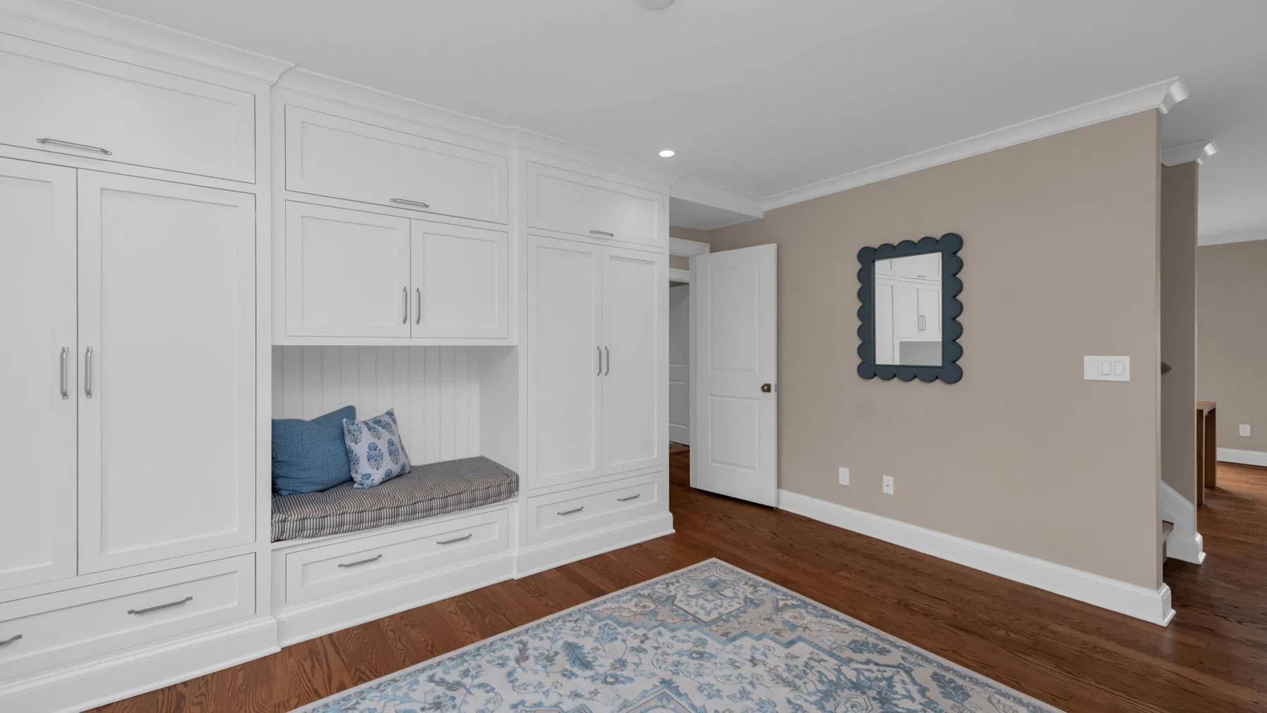 A bright bedroom features built-in white cabinetry and a cushioned window seat.