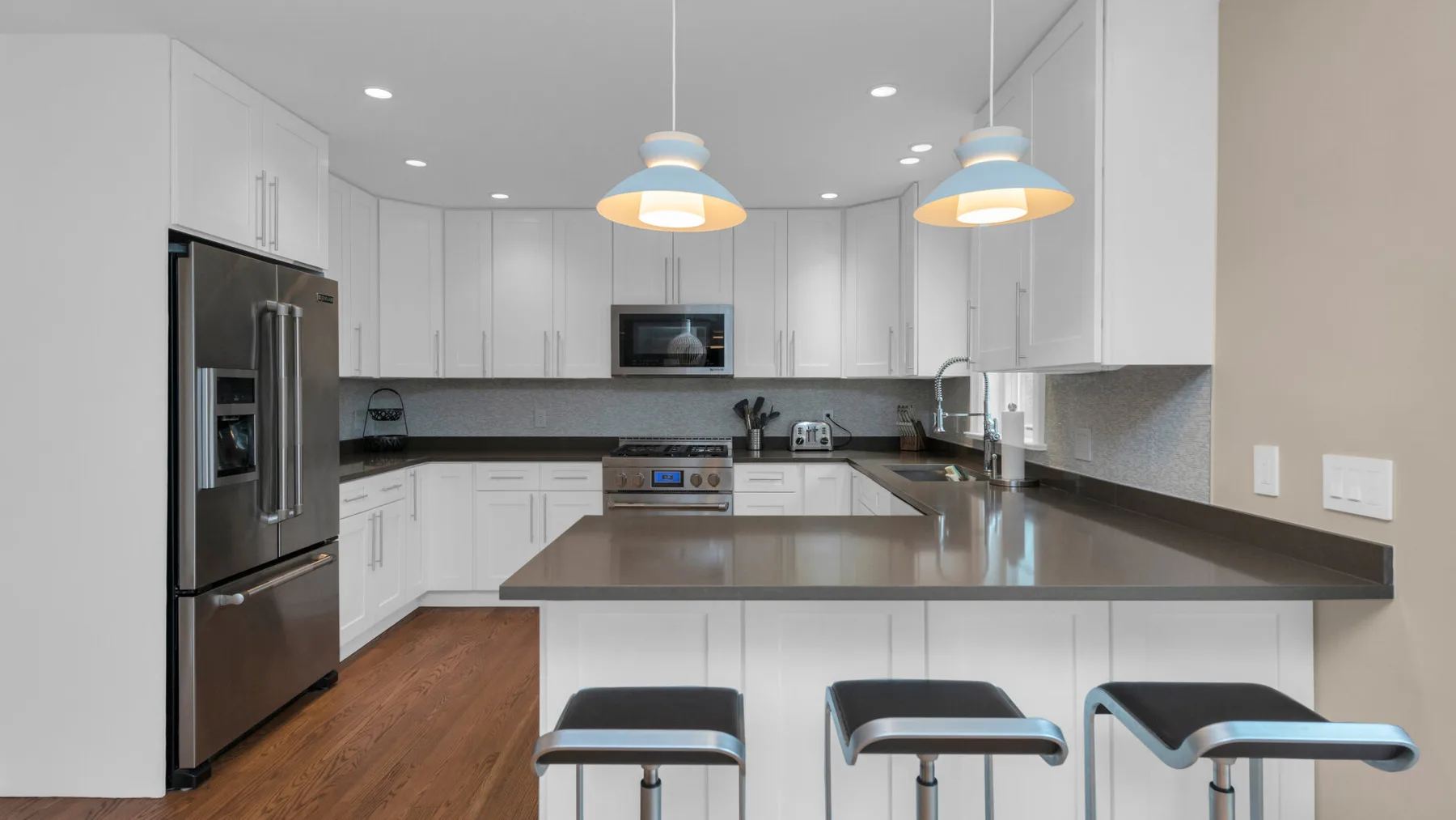 A bright kitchen with white cabinets, stainless steel appliances, and a central island.