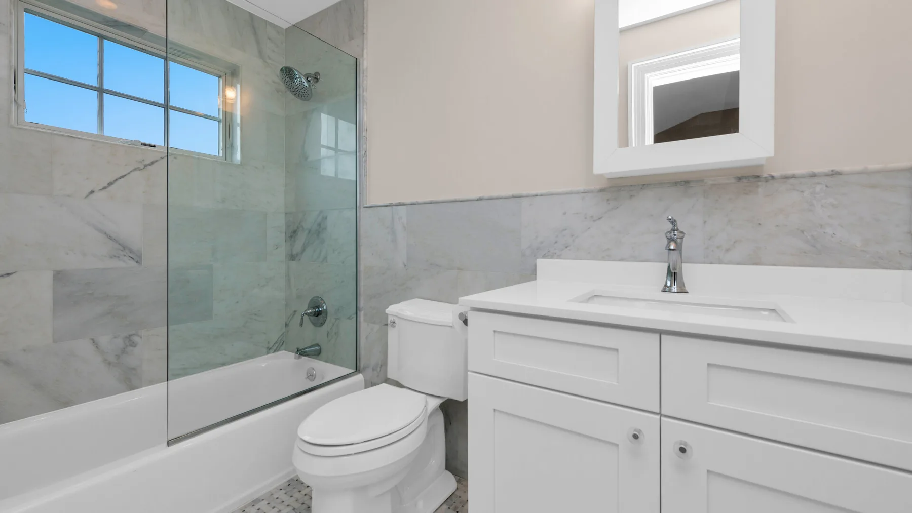 A bright bathroom with a bathtub, toilet, and white vanity.