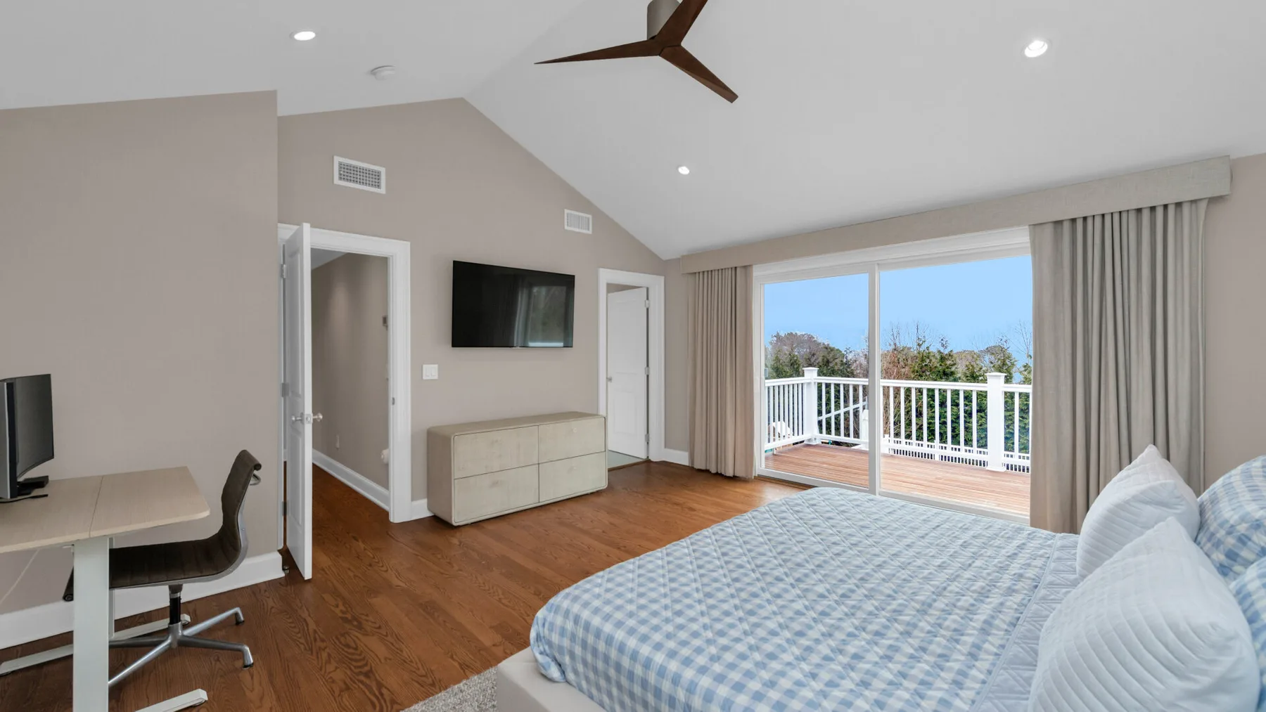 A bright bedroom with a bed beside sliding glass doors opening onto a balcony.