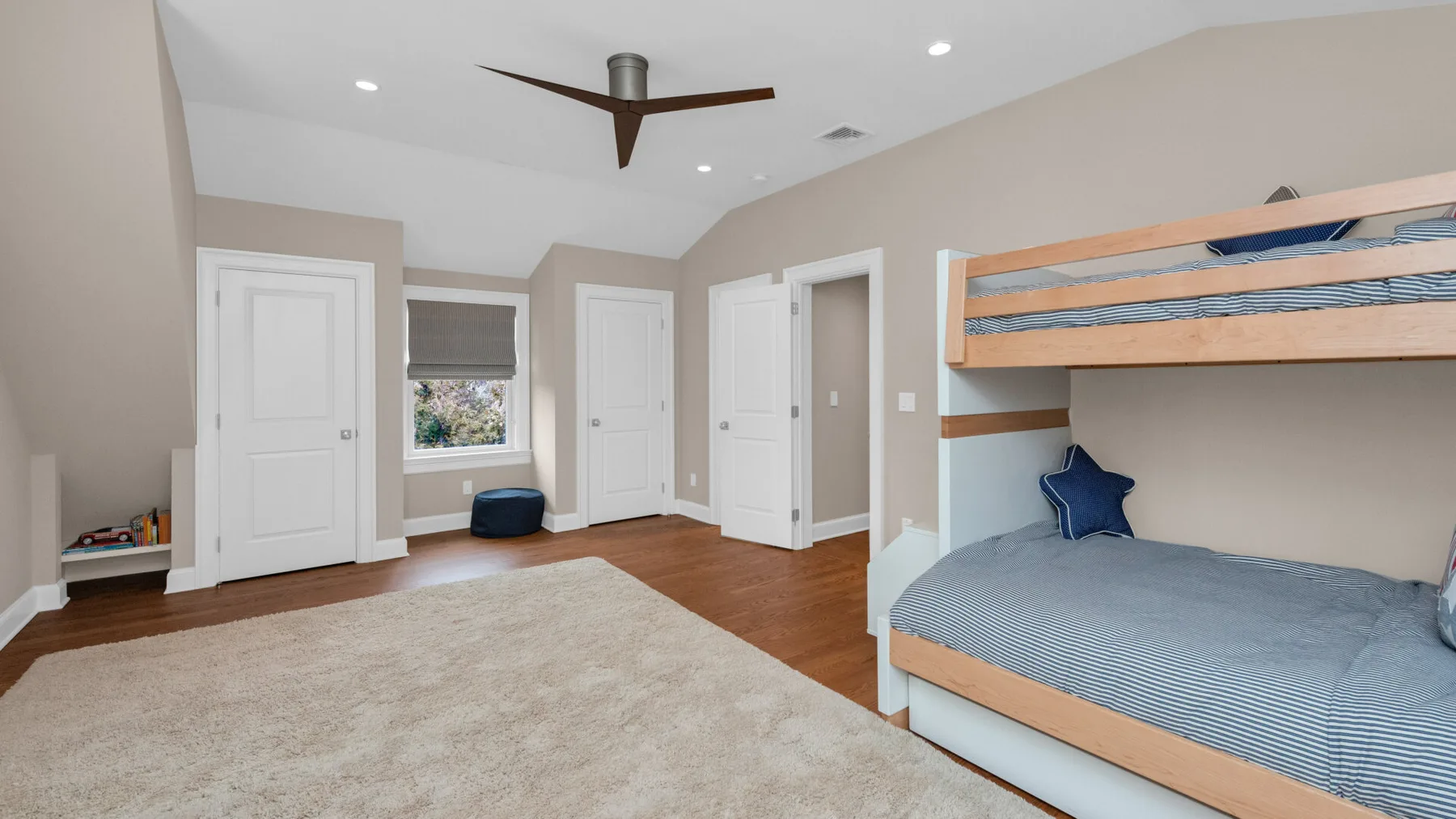 A bedroom with bunk beds, a large rug, and several white doors.