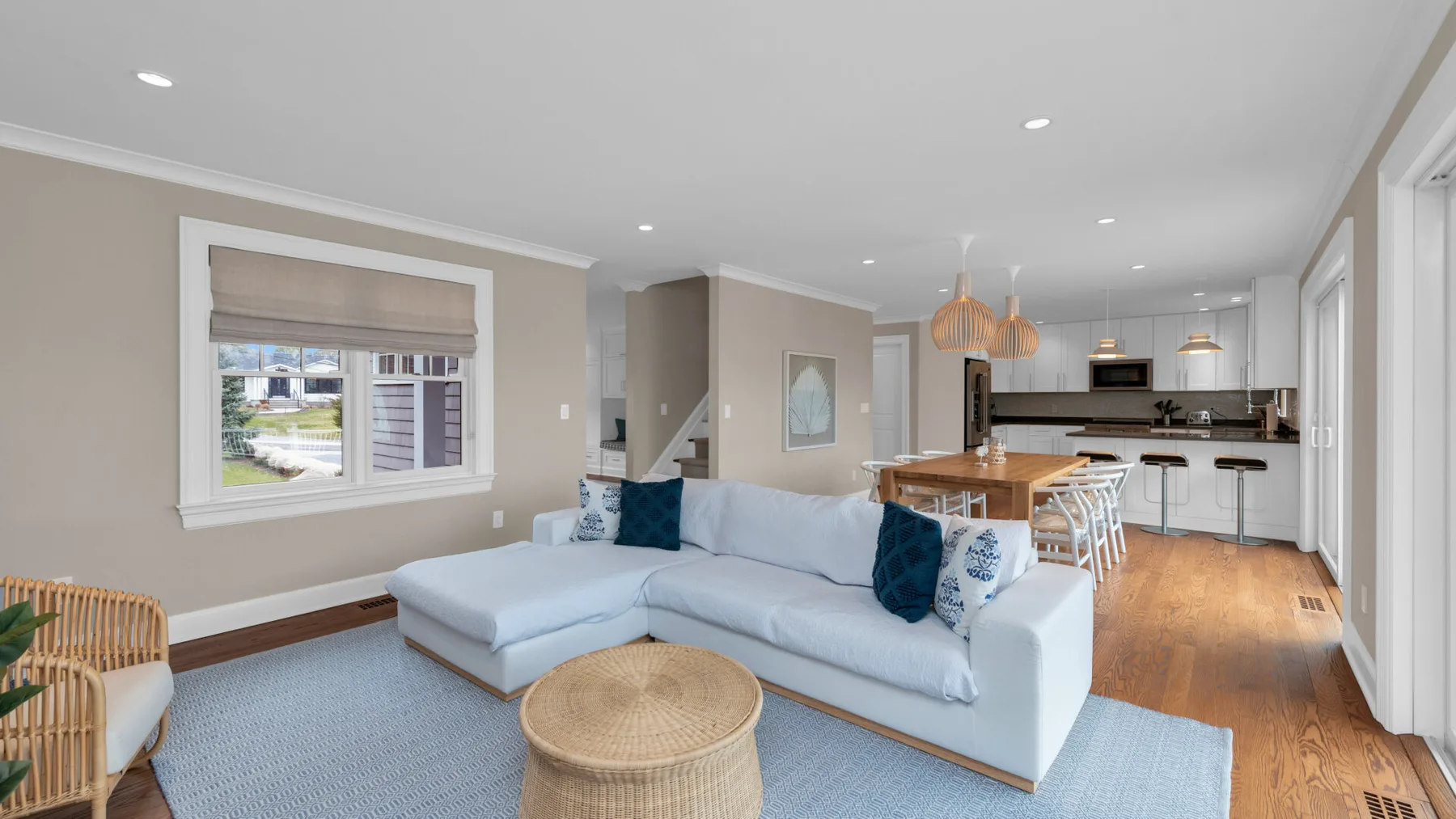 A bright living room with a sectional sofa and an open kitchen-dining area.