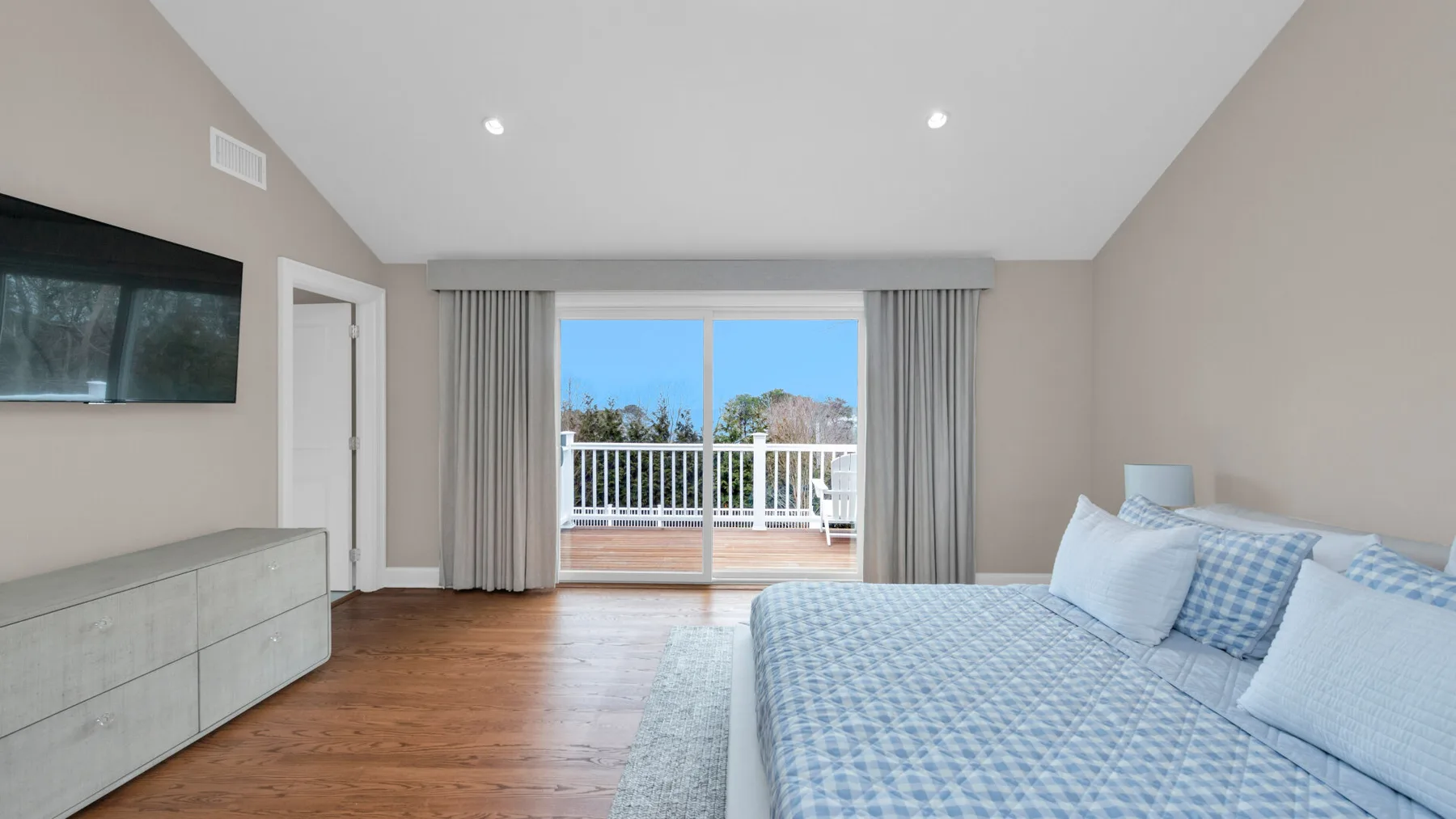 A bedroom with a bed beside sliding glass doors opening to a balcony.