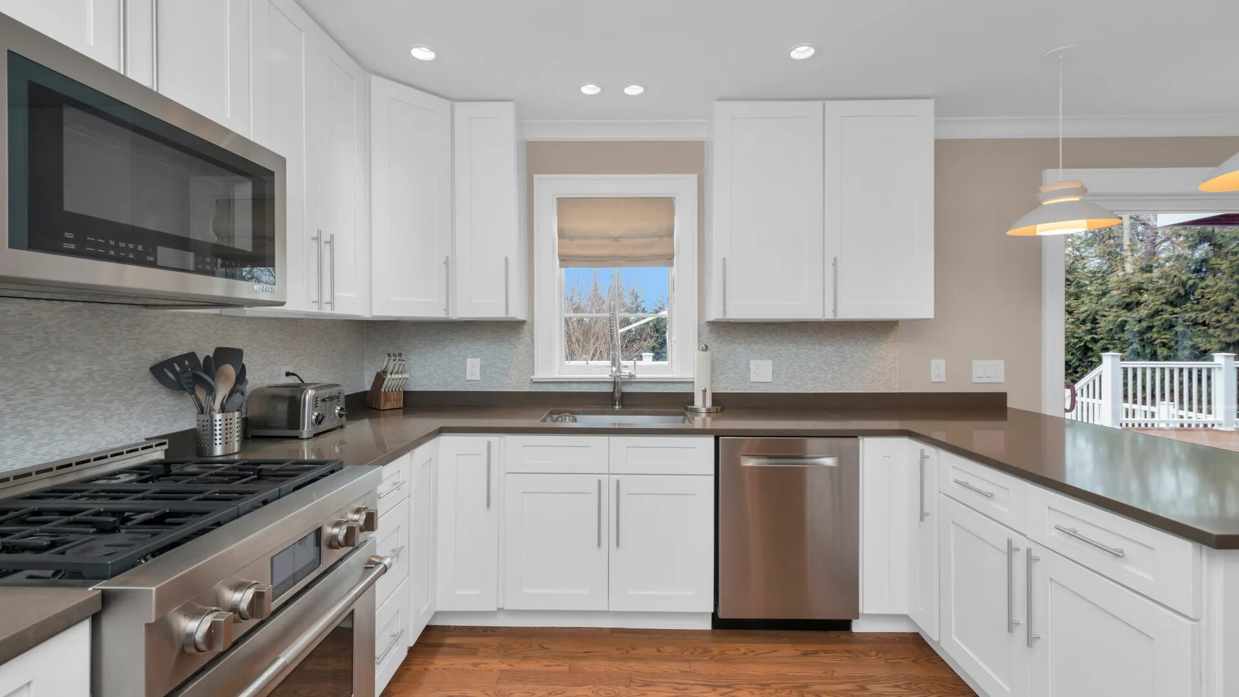 A bright white kitchen with an L-shaped counter and stainless steel appliances.