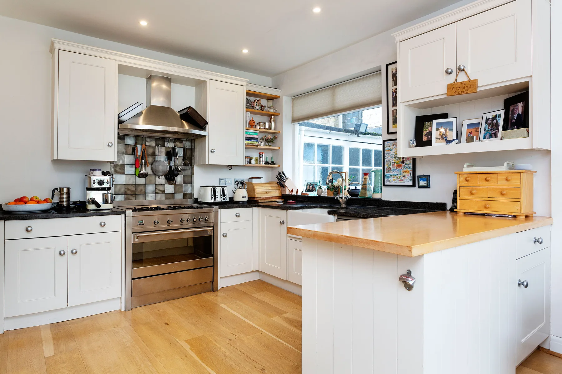 A bright kitchen with white cabinets, a central island, and a large window.