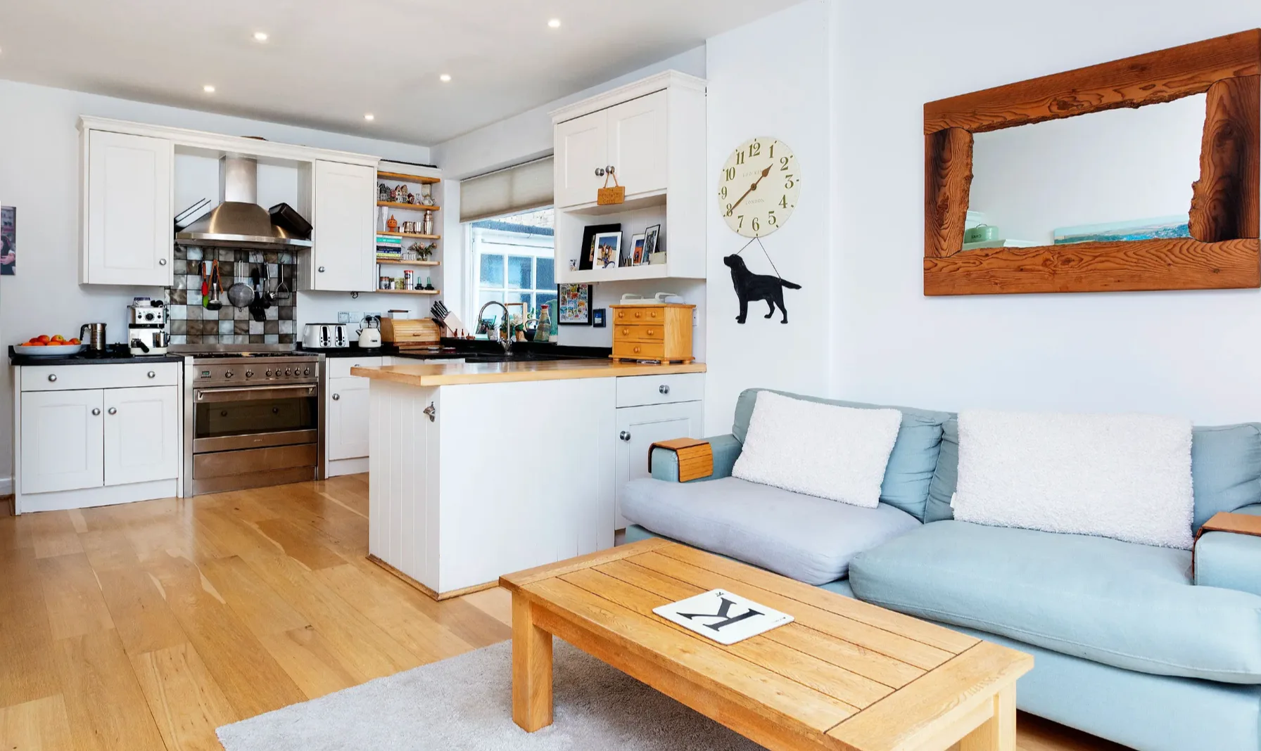An open-plan kitchen and living area with a light blue sofa and wooden coffee table.