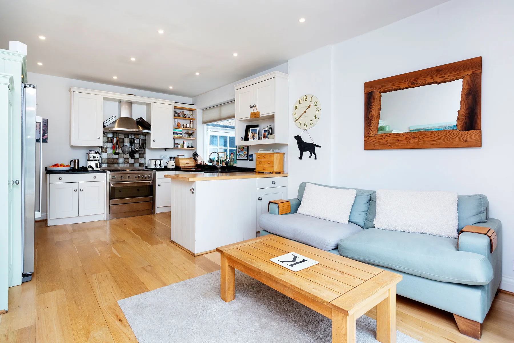 A bright open-plan living room and kitchen with a pale blue sofa.