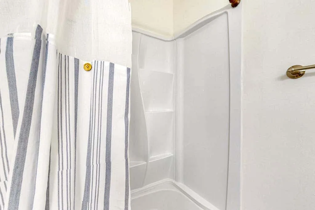 A shower with built-in shelves and a striped curtain.