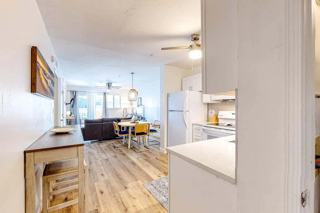 An open-plan living and dining area with a kitchen and light wood flooring.