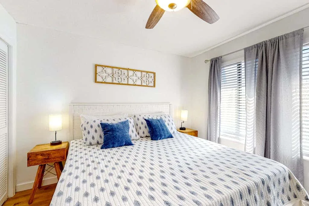 A bedroom with a patterned bedspread and blue accent pillows.